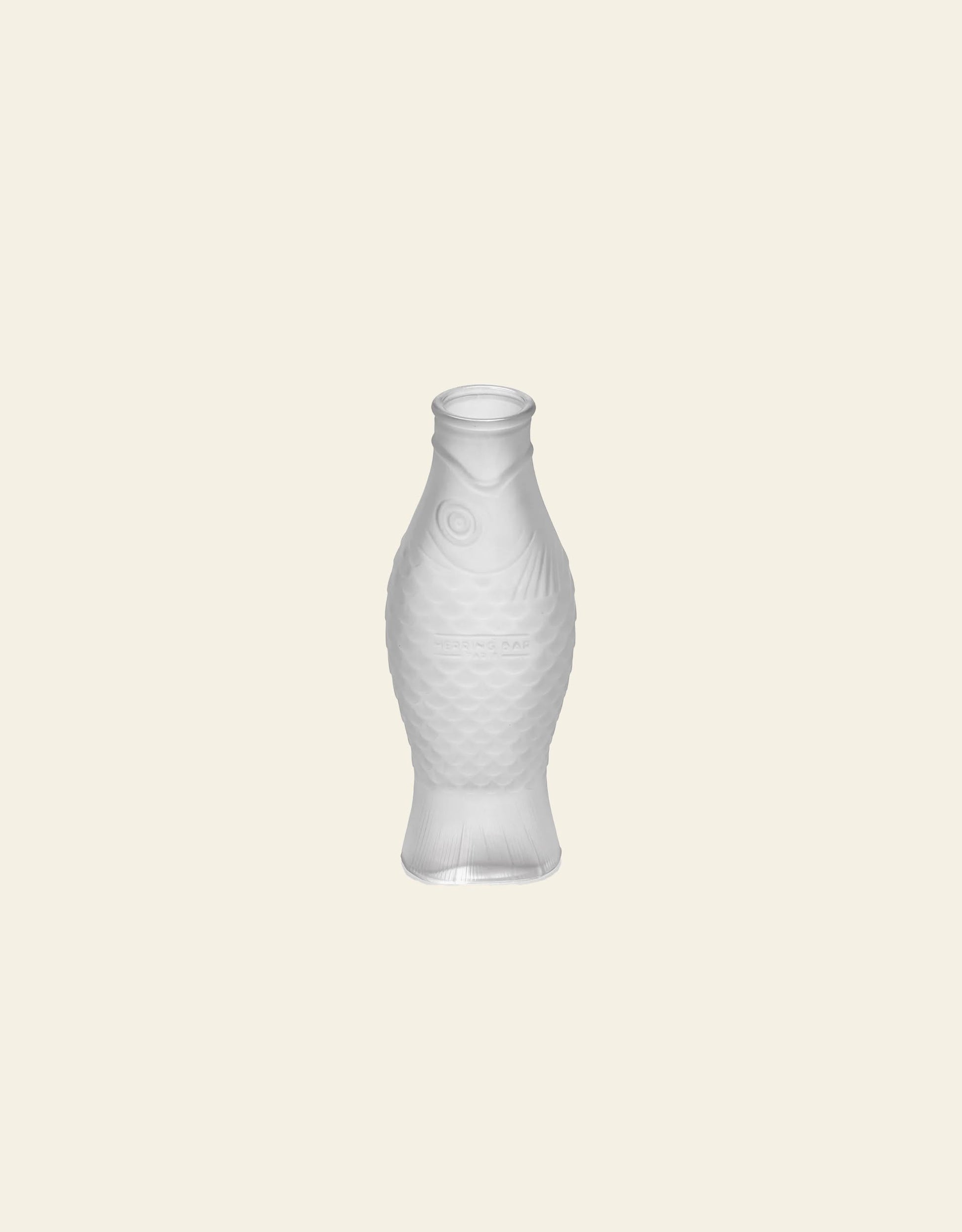 The Serax Fish & Fish Carafe by Serax, with its translucent, textured fish design, stands upright on a light beige background—an eye-catching piece to bring unique charm to your tableware setting.