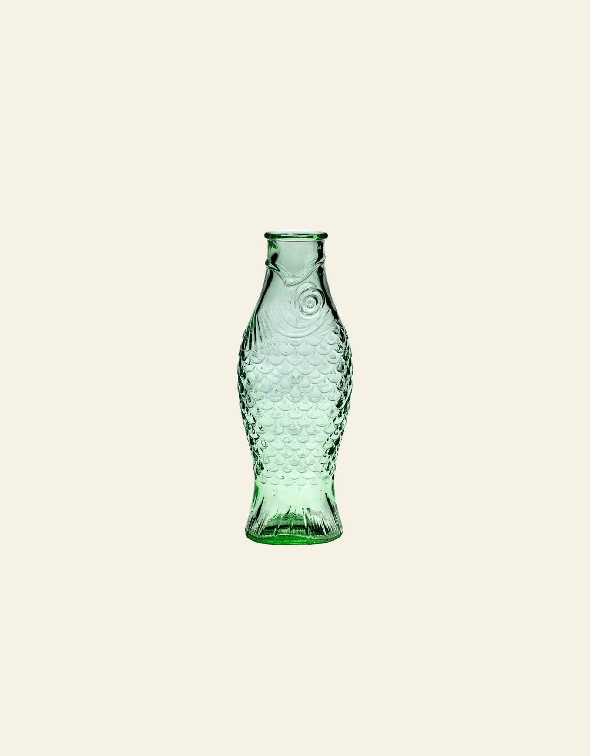 The Serax Fish & Fish Carafe - Green is a glass bottle shaped like a fish, featuring detailed scales and fins, designed by Paola Navone for Serax, shown upright against a plain beige background.