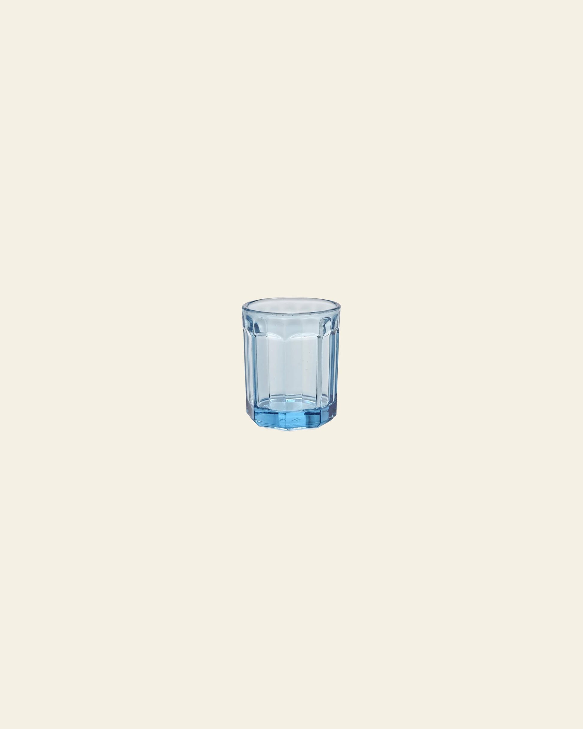 A small, transparent blue Serax Fish & Fish Glass M by Serax is centered on a plain, light beige background, its cool hue inspired by the brand’s iconic collection.