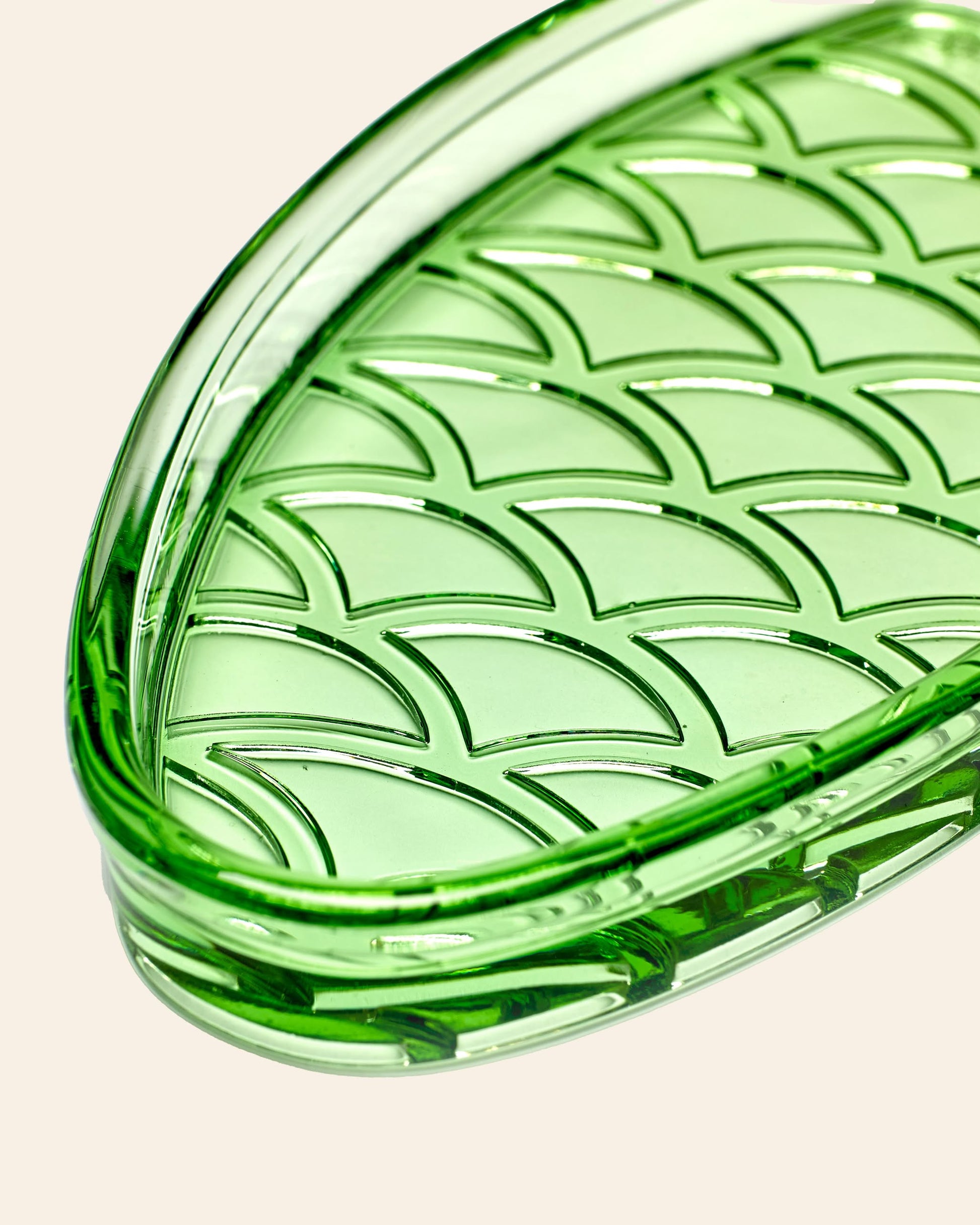 A close-up of the Serax Fish & Fish Serving Dish N°1 - Green, featuring an oval shape and a raised overlapping scale pattern from Serax, shown against a neutral beige background.