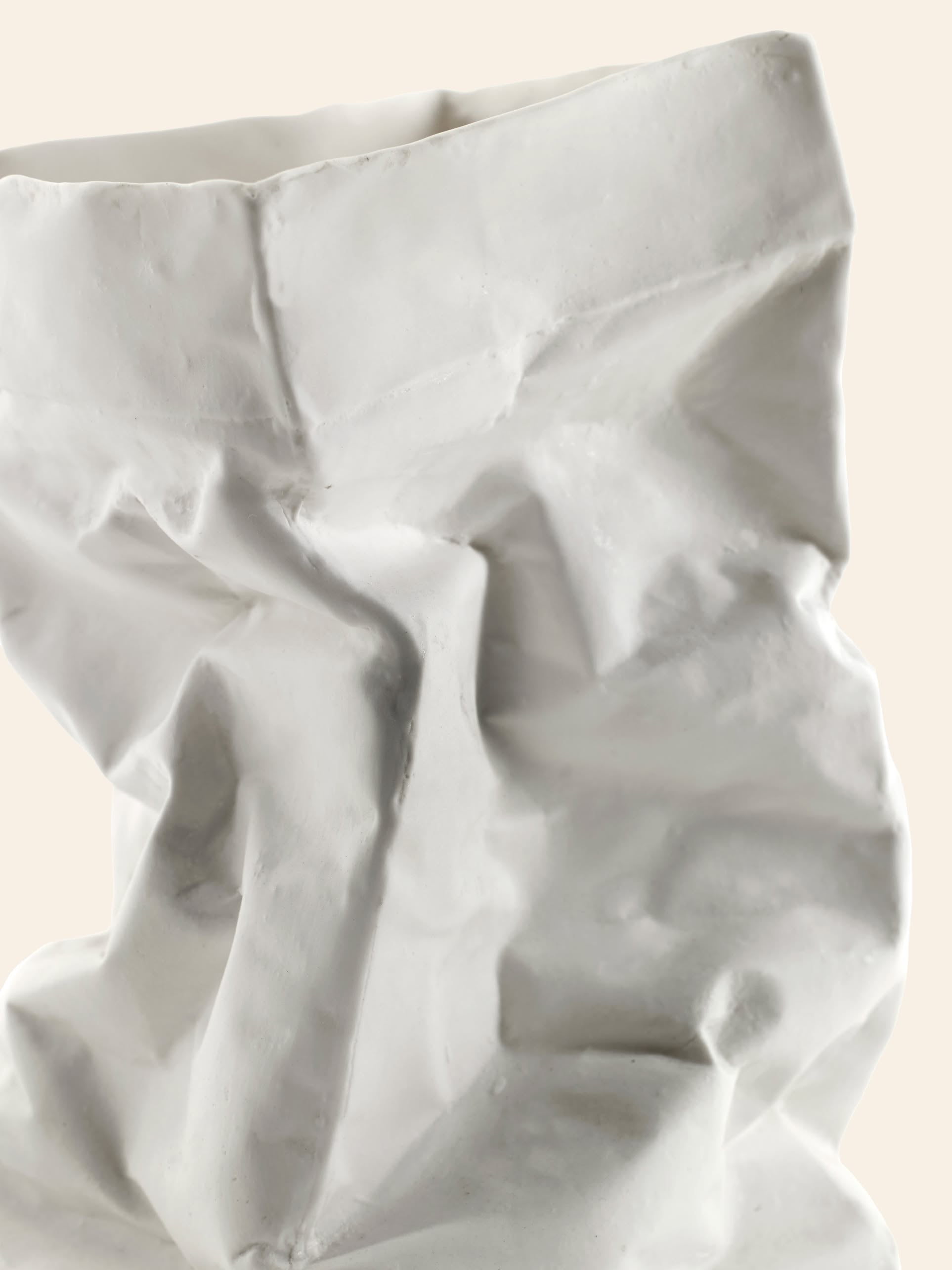 The Serax Kiki Paperbag L - White, by Serax, is a porcelain sculpture styled like a crumpled paper bag with textured folds, reflecting Dutch design influences and displayed elegantly against a neutral background.