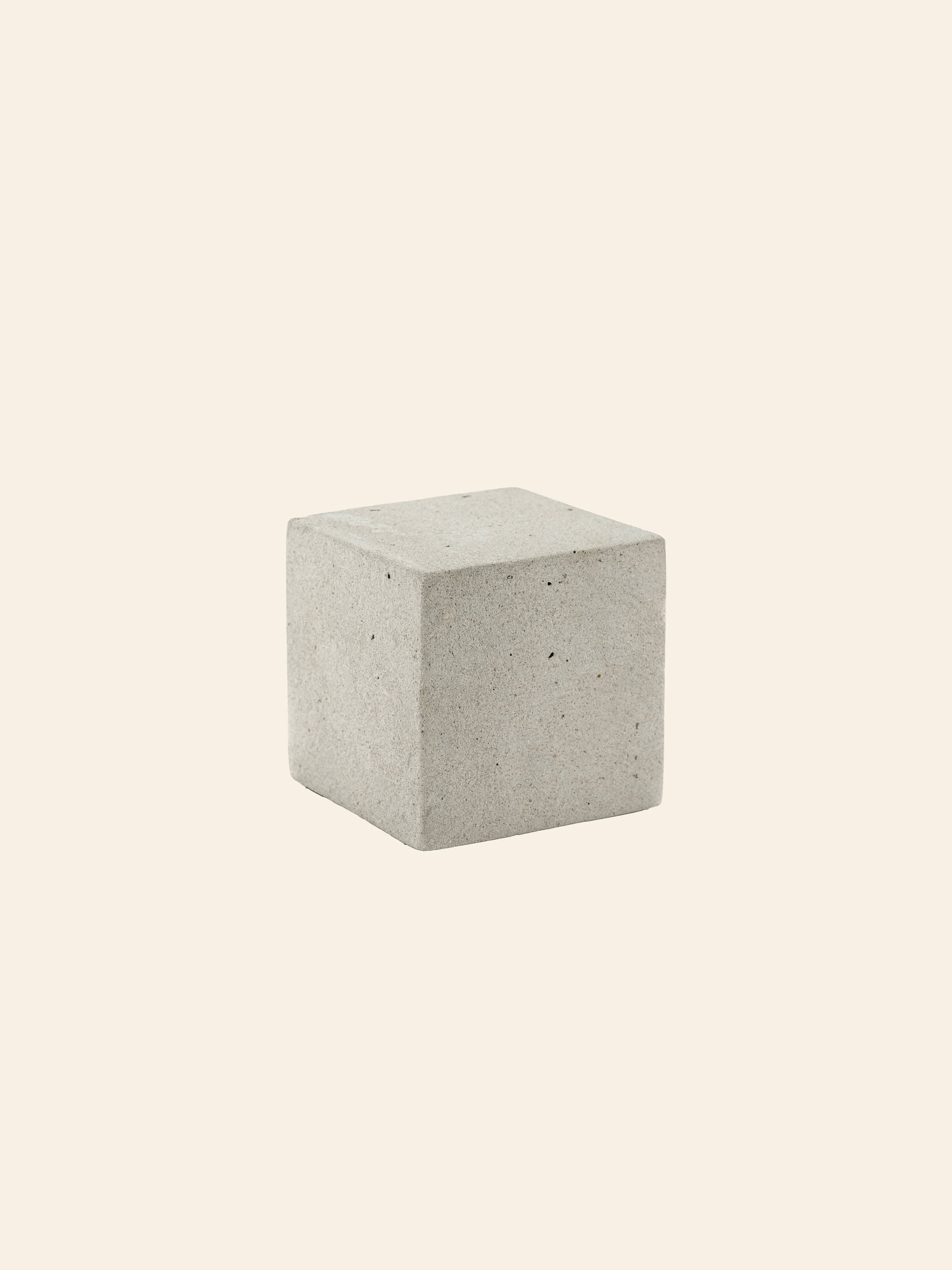 The Serax Marie Cube Concrete in grey by Serax rests on a light beige background, its smooth finish and clean lines offering an industrial accent—ideal for contemporary decor.