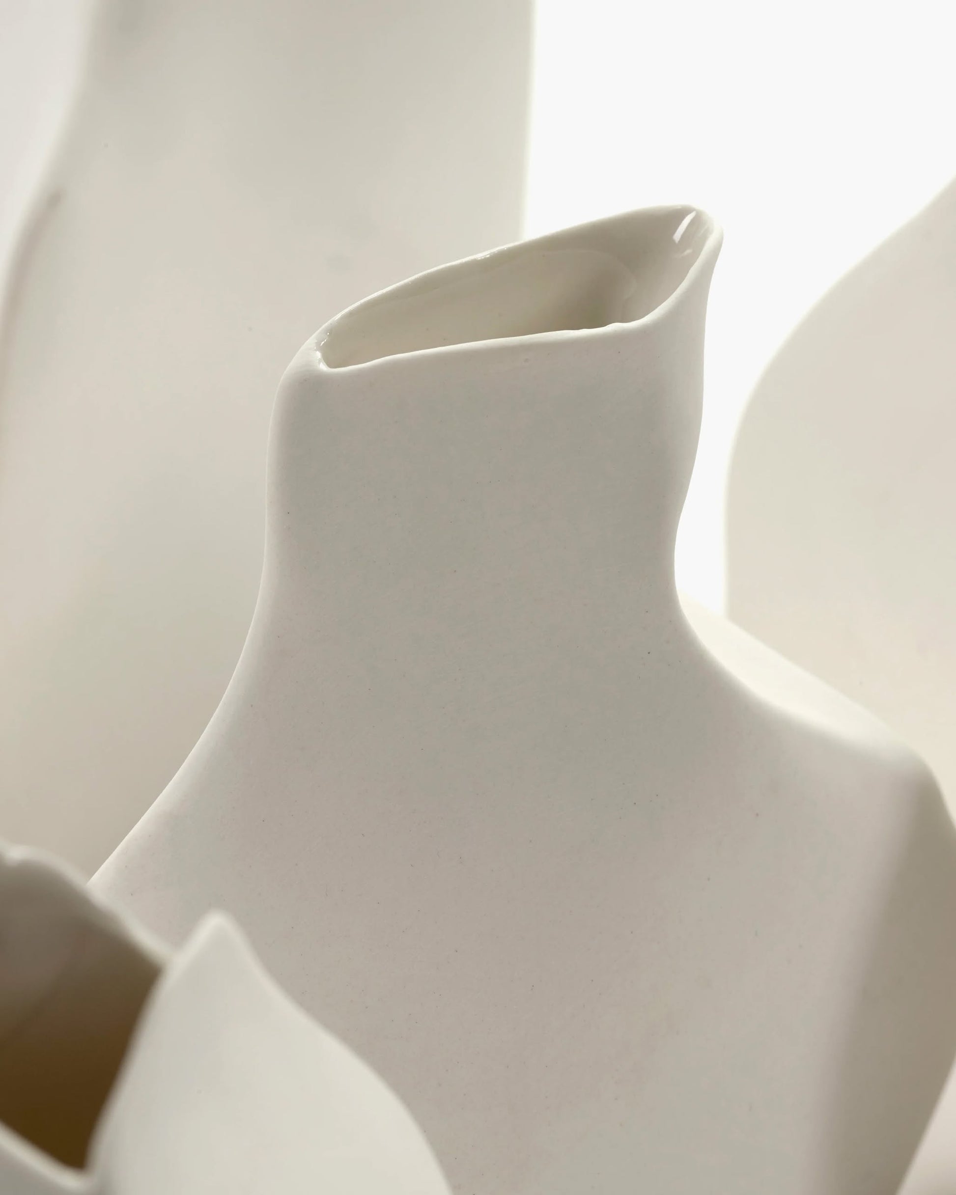 A close-up of the Serax Perfect Imperfection Flower Vase N°5 in white, featuring smooth, abstract lines and angled openings, reflects Serax’s handcrafted style against a light background.