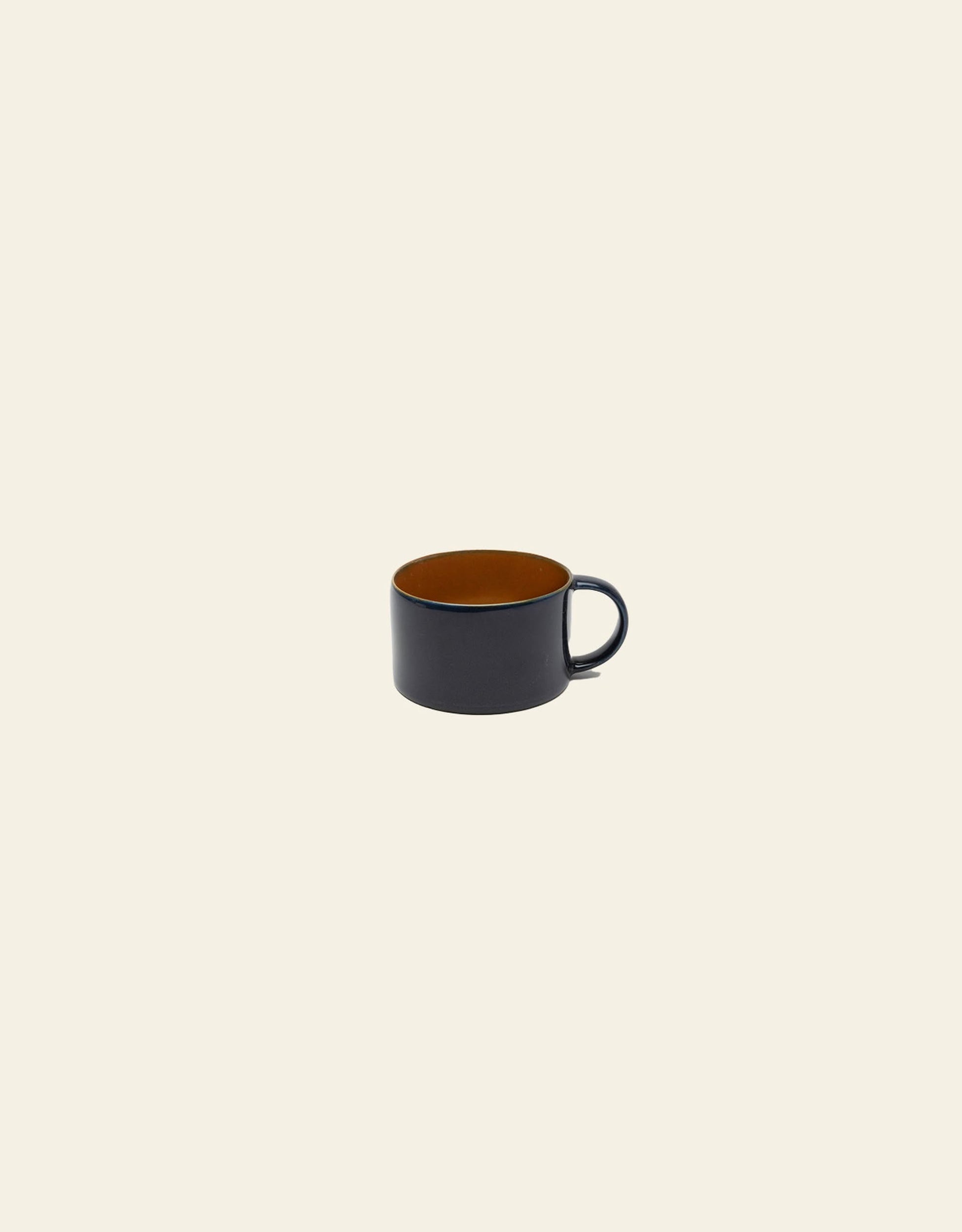 The Serax Terres De Rêves Coffee Cup by Serax, handcrafted from black stoneware with a brown interior, sits centered on a plain light beige background.
