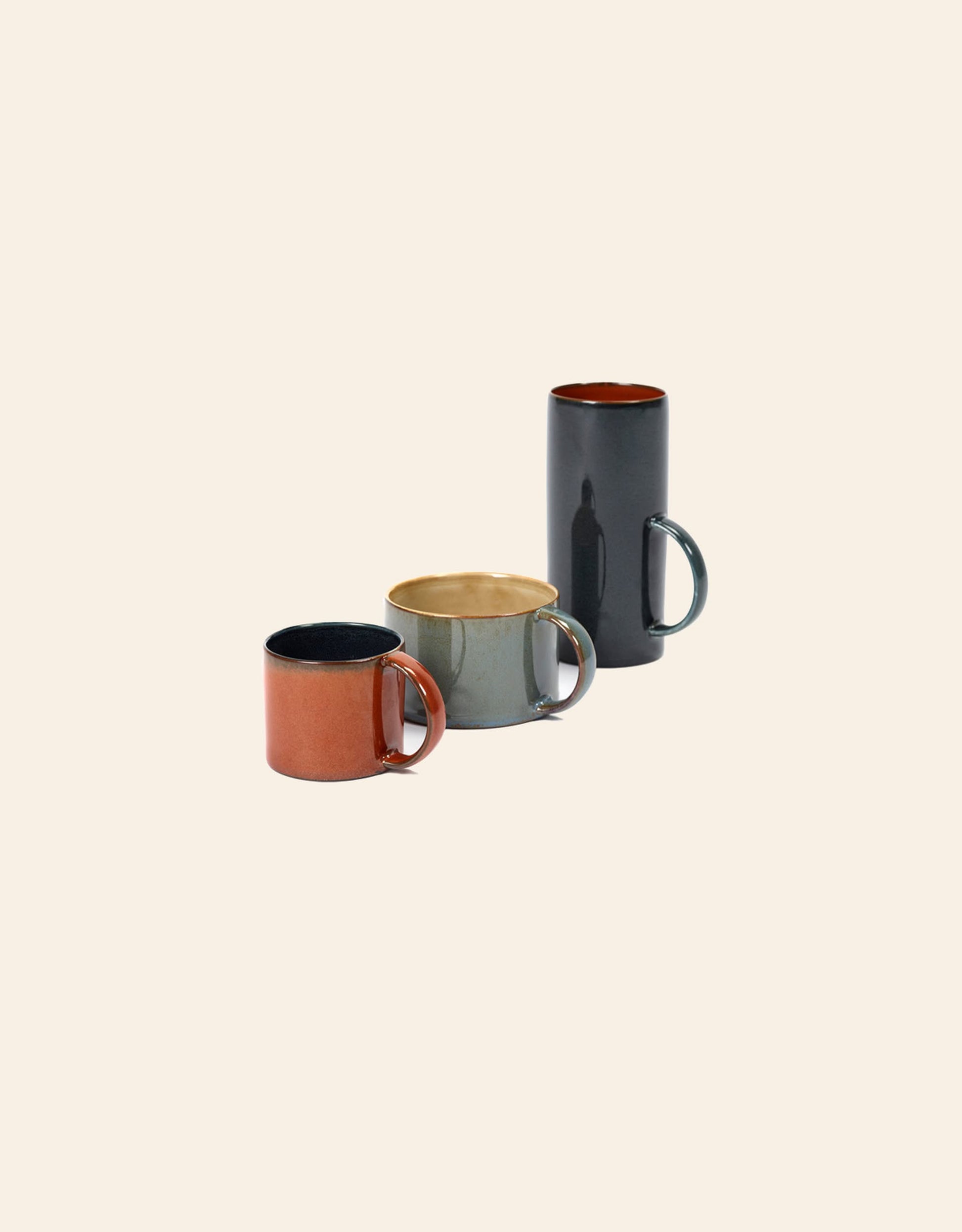 Three Serax Terres De Rêves Coffee Cups by Serax—one red, one gray, and one tall black—are arranged in a staggered line on a plain, light beige background.