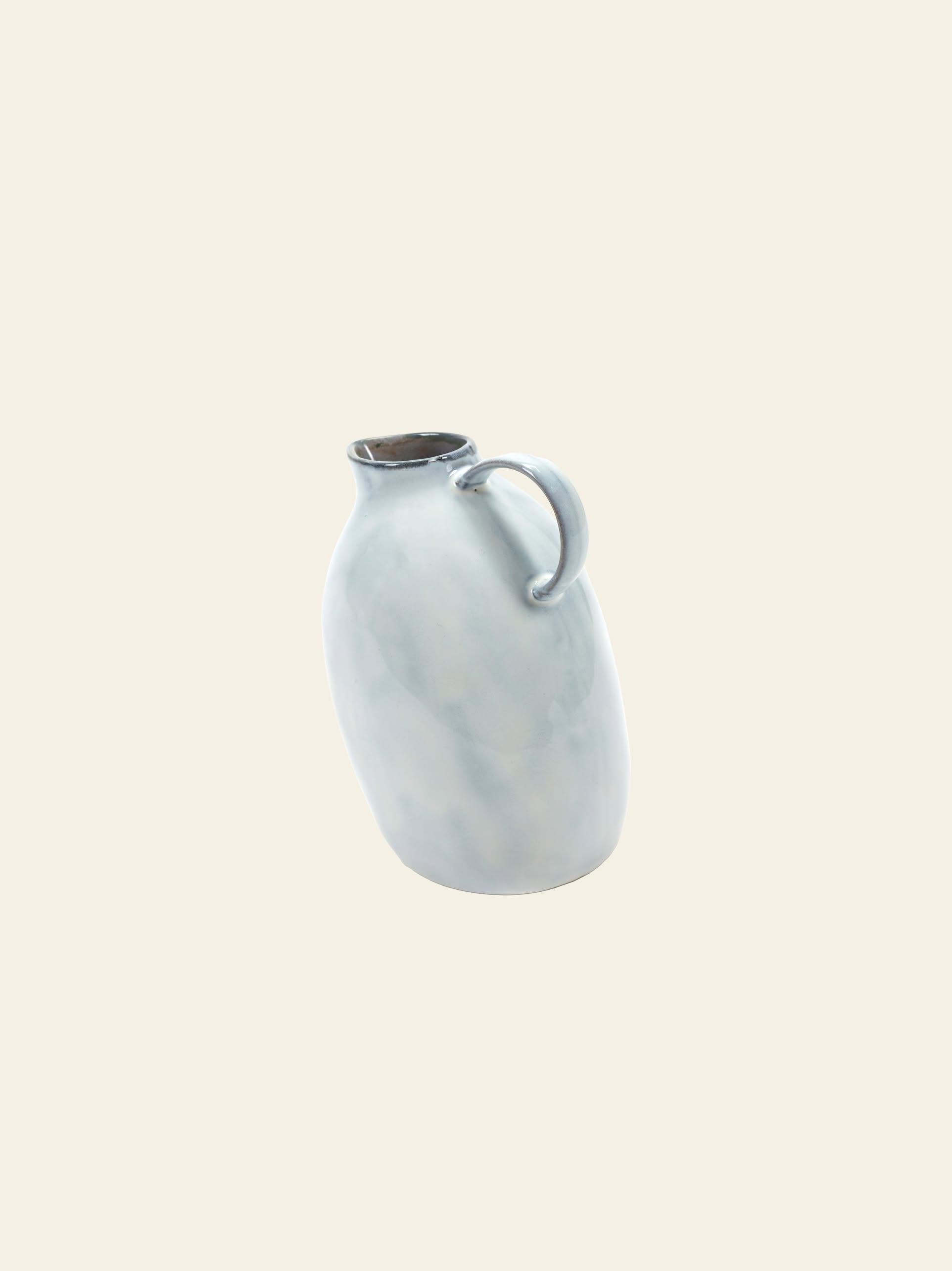 The Serax Terres De Rêves Jug °1 - White by Serax features a rounded body, narrow neck, and small handle, offering an unconventional ceramic design that stands out subtly against a plain off-white background.