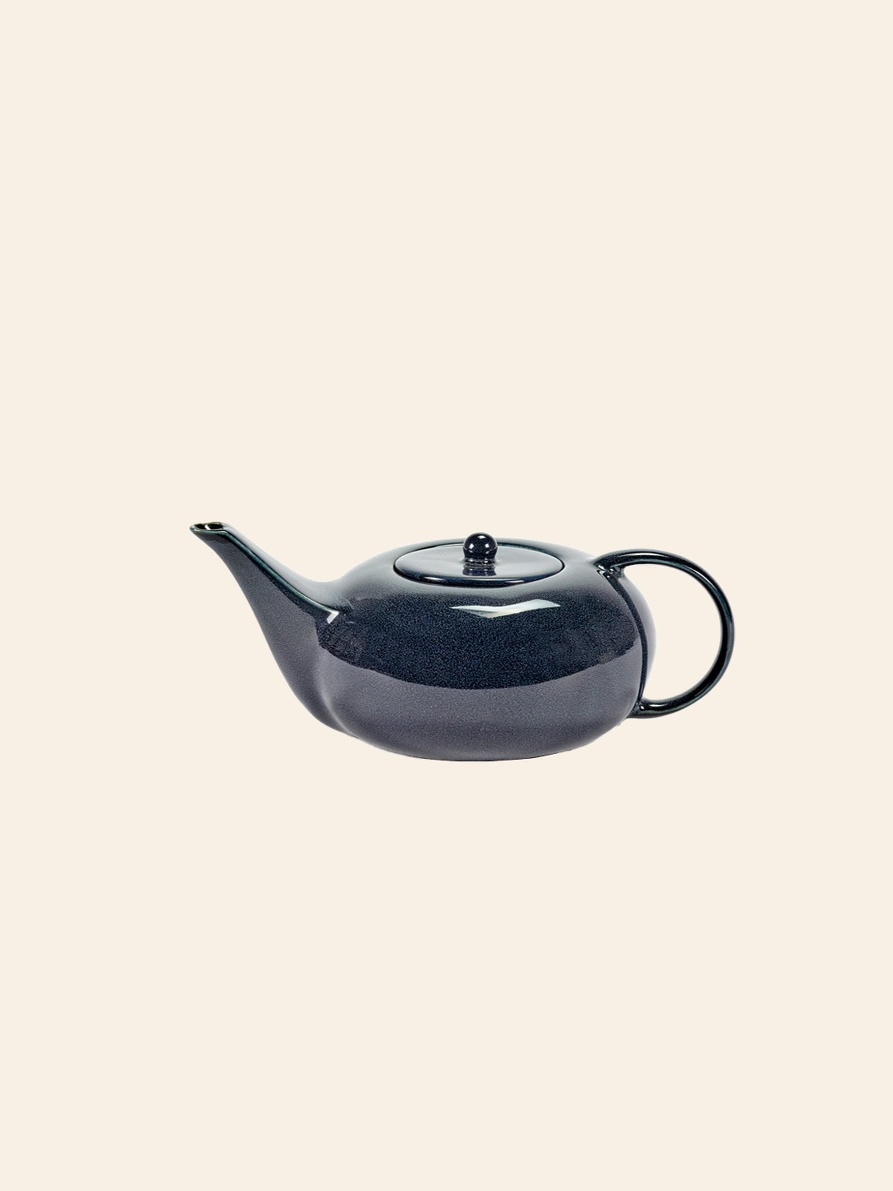 The Serax Terres De Rêves Teapot in dark blue by Serax features a glossy ceramic finish, round body, curved spout, and circular handle, shown against a plain cream-colored background.