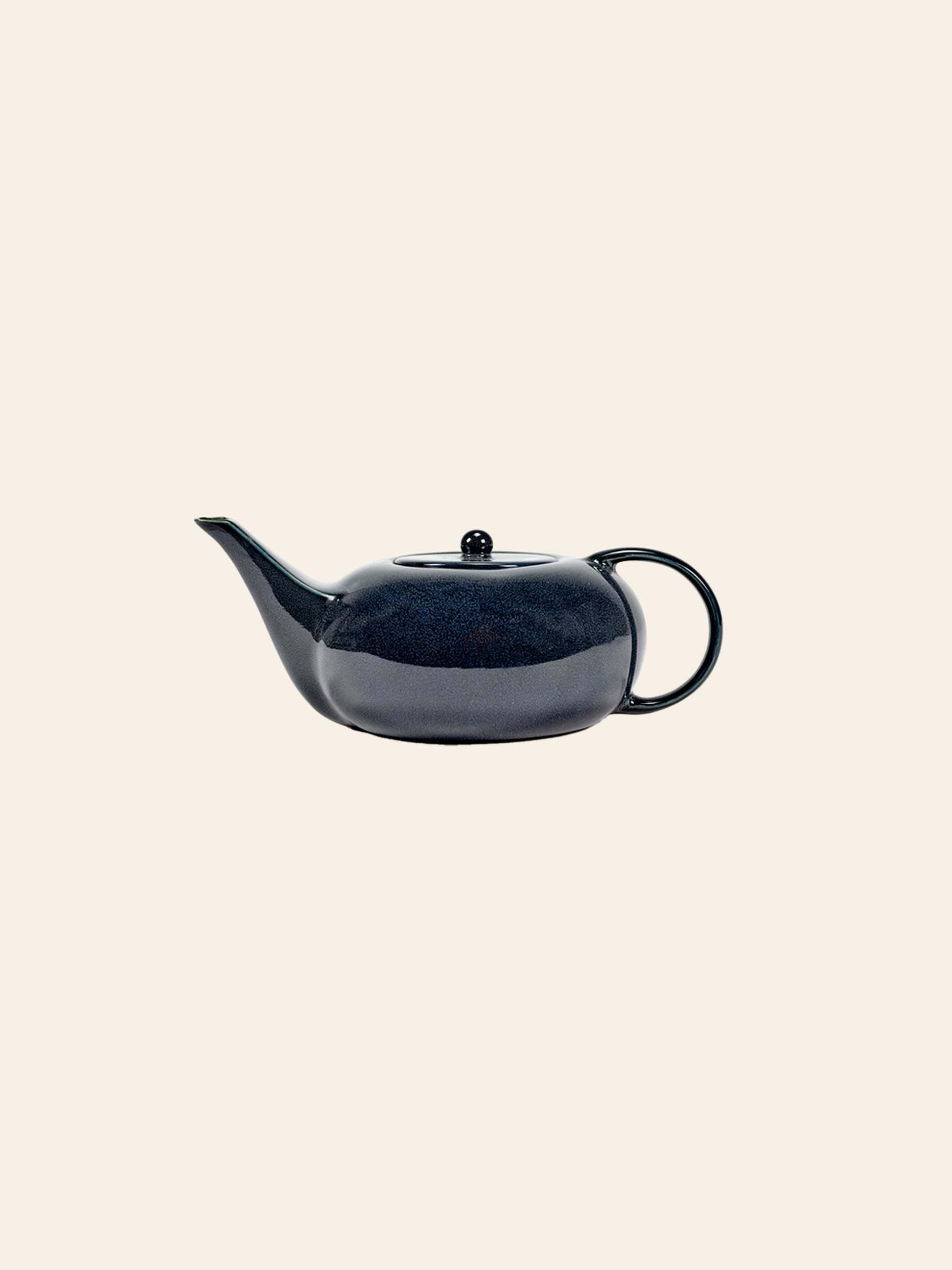 The Serax Terres De Rêves Teapot in dark blue, featuring a curved spout, round handle, and matching lid, sits elegantly against a light beige background—an ideal addition to your refined tableware collection.