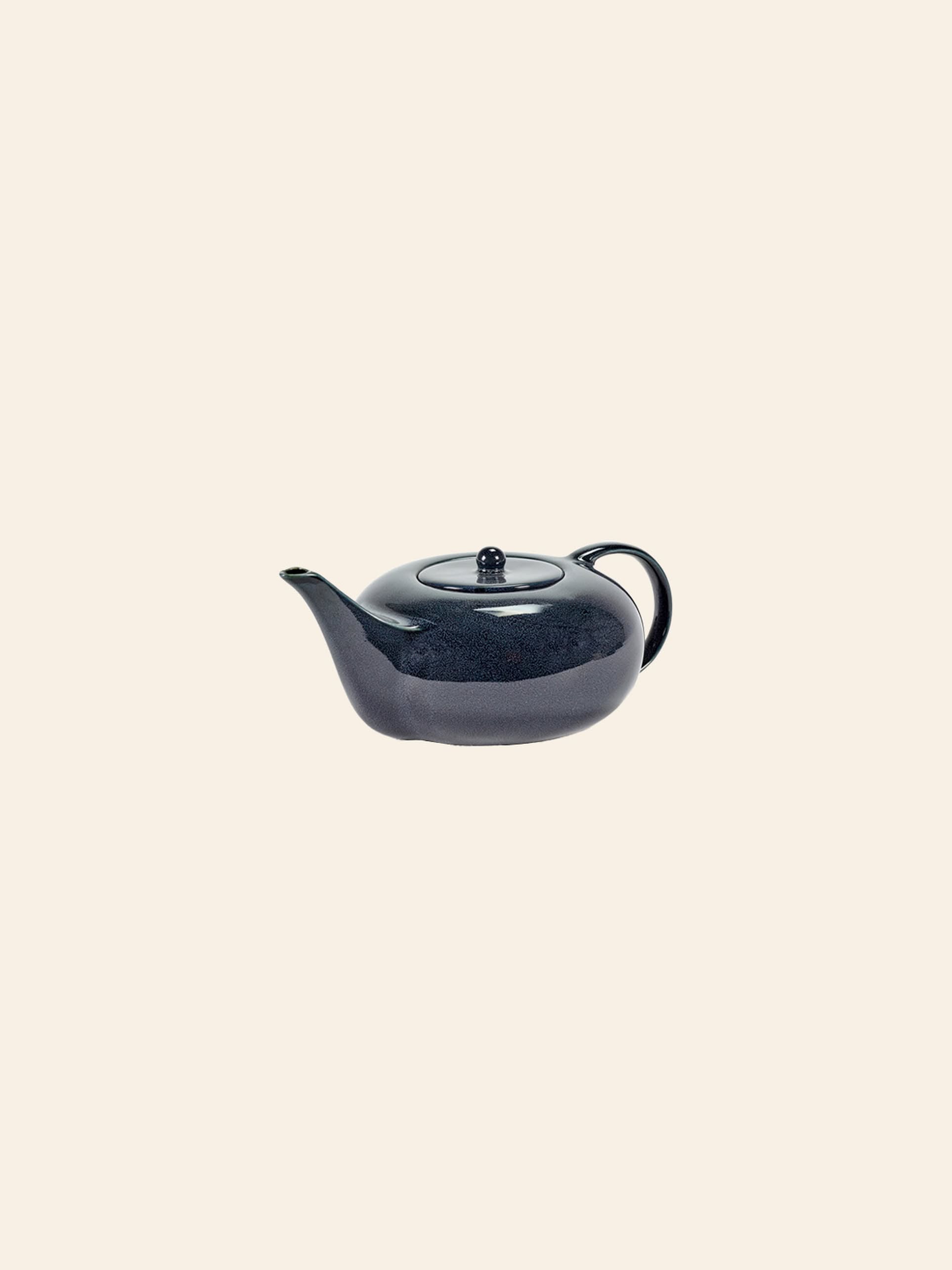 The Serax Terres De Rêves Teapot by Serax features a glossy dark blue rounded body, short spout, and small curved handle—an elegant tableware piece—presented against a plain light beige background.