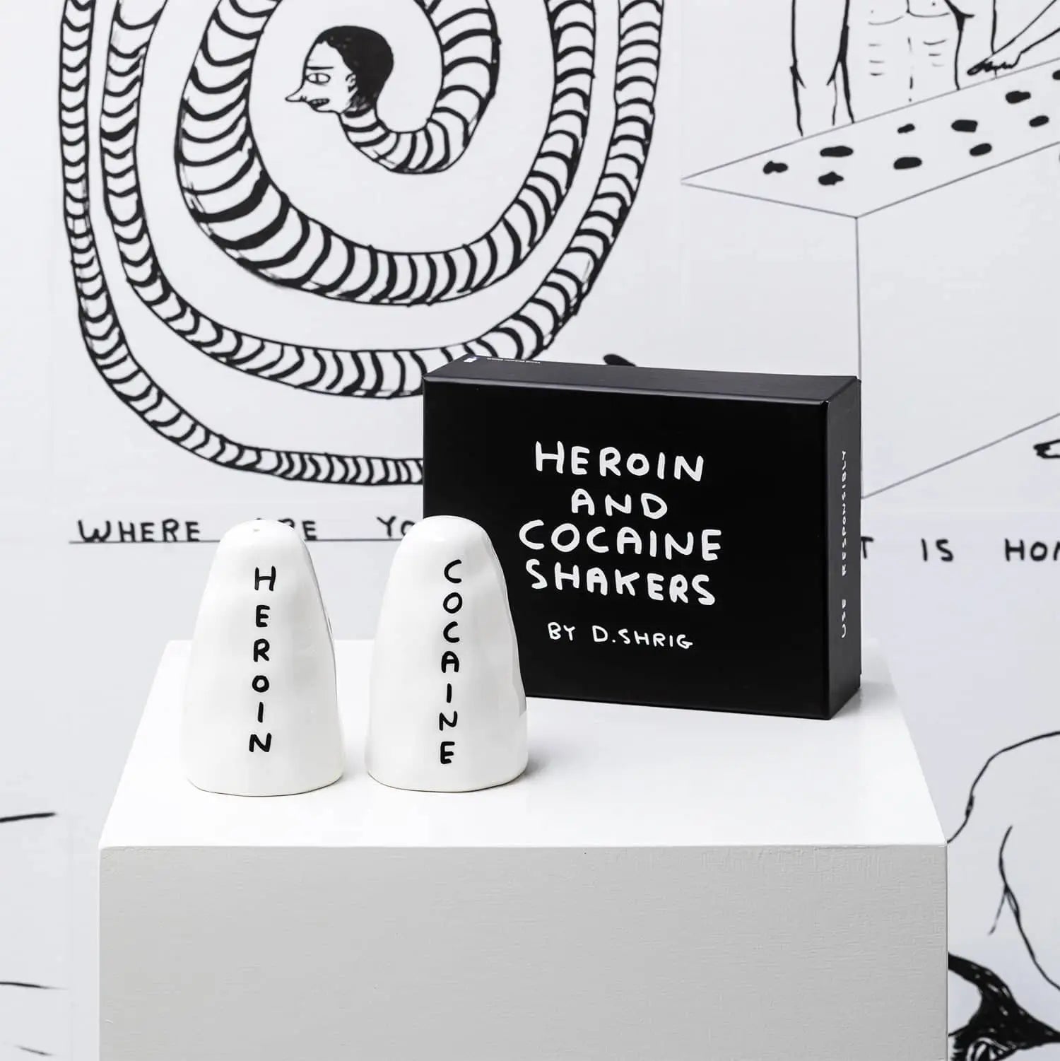 Shrig Shop Heroin and Cocaine Porcelain Shakers by Shrig Shop sit beside a black box on a white pedestal, featuring bold cartoon art and making unique collectibles.