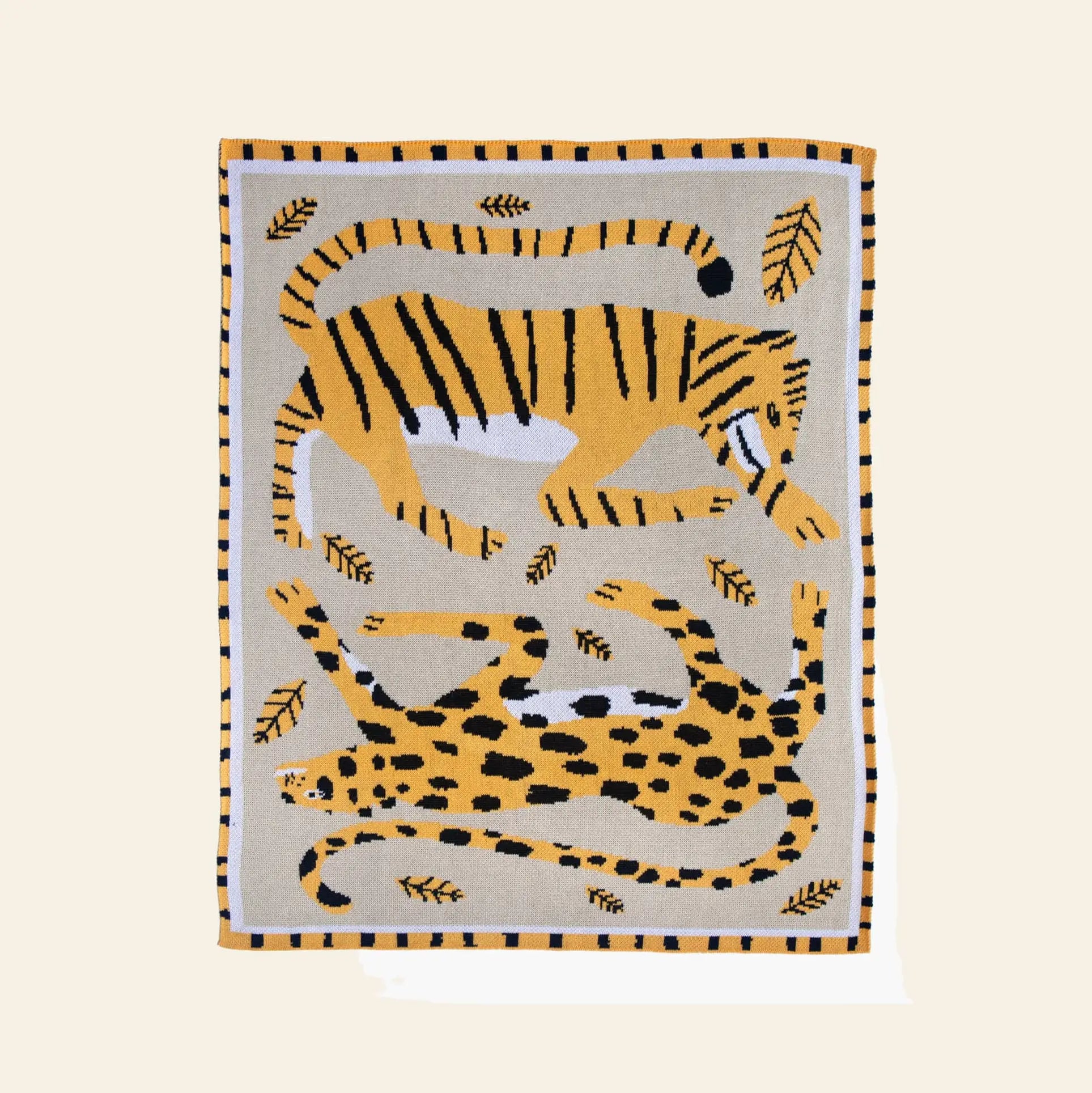 The Slowdown Studio Big Cats Mini Blanket is a rectangular throw featuring tiger and leopard designs among leaves, crafted from a recycled cotton blend in yellow, black, and white on beige.