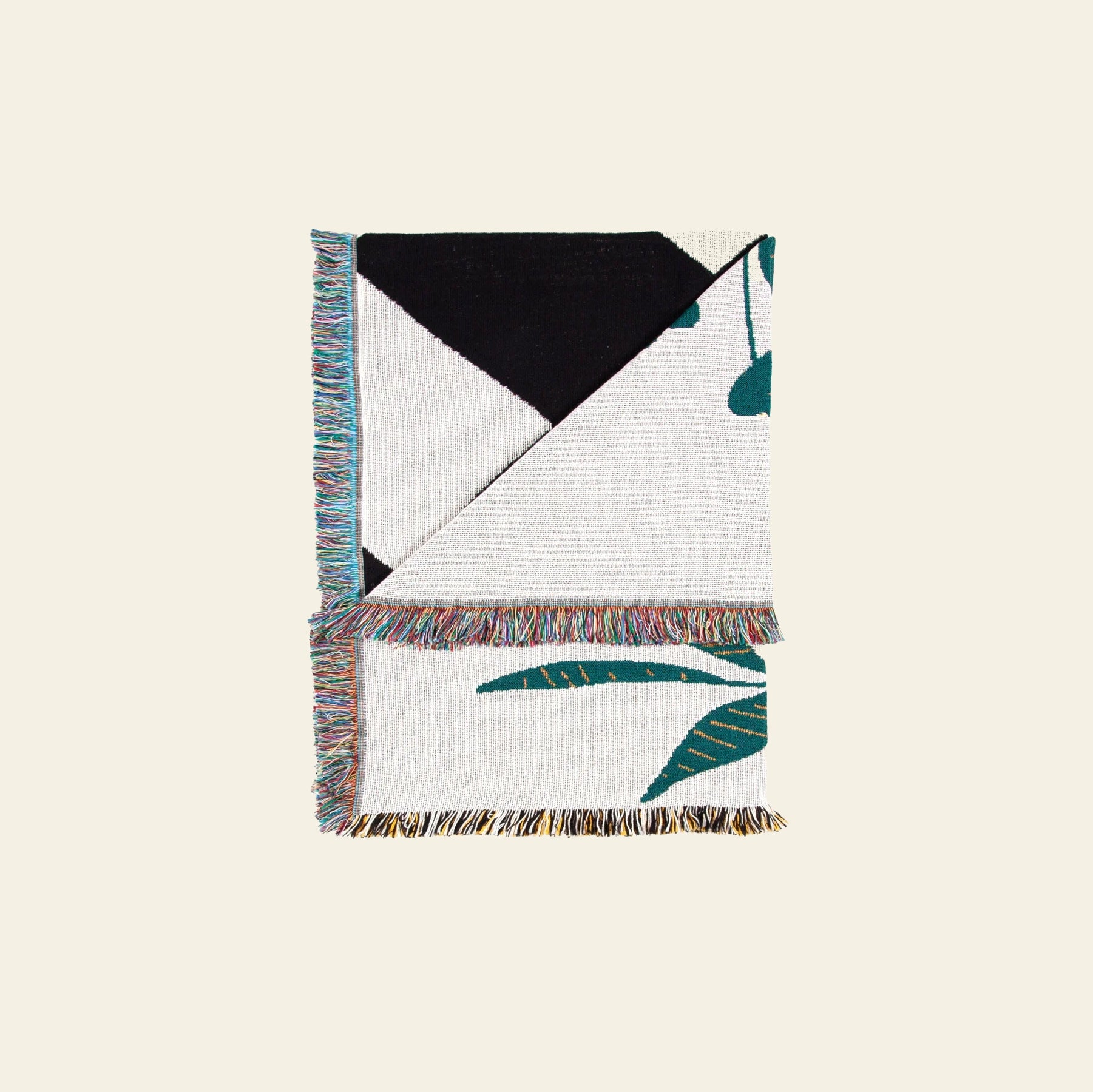 The Slowdown Studio Dresden Throw by Slowdown Studio is a folded woven blanket made from recycled cotton, featuring an abstract black, green, and beige design on a light background with multicolored fringe—an eye-catching accent for any space.