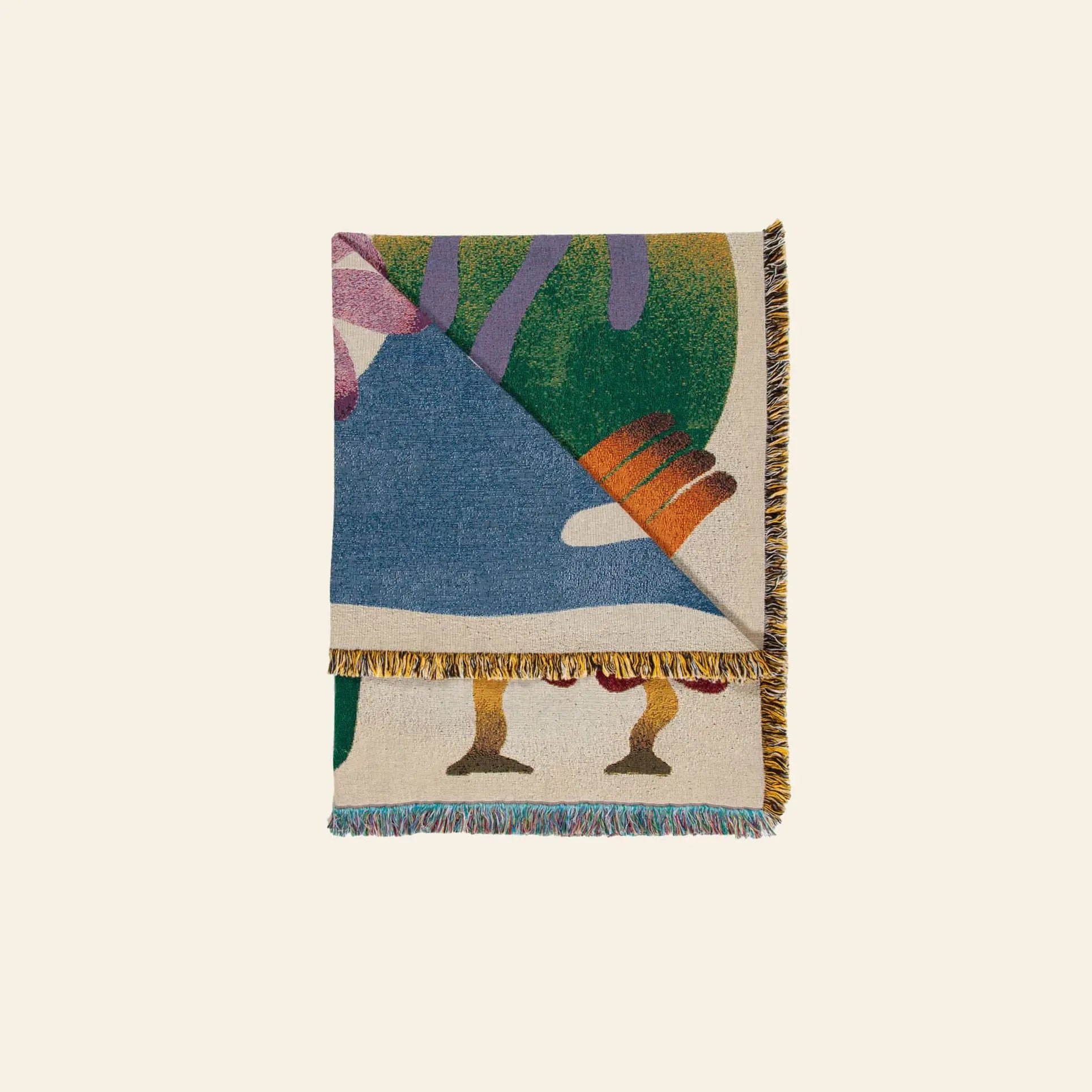 The Slowdown Studio Dumont Throw features colorful abstract patterns in blue, green, pink, orange, and yellow with a multicolored fringe. Made from recycled cotton, it’s shown folded and stacked on a light background.