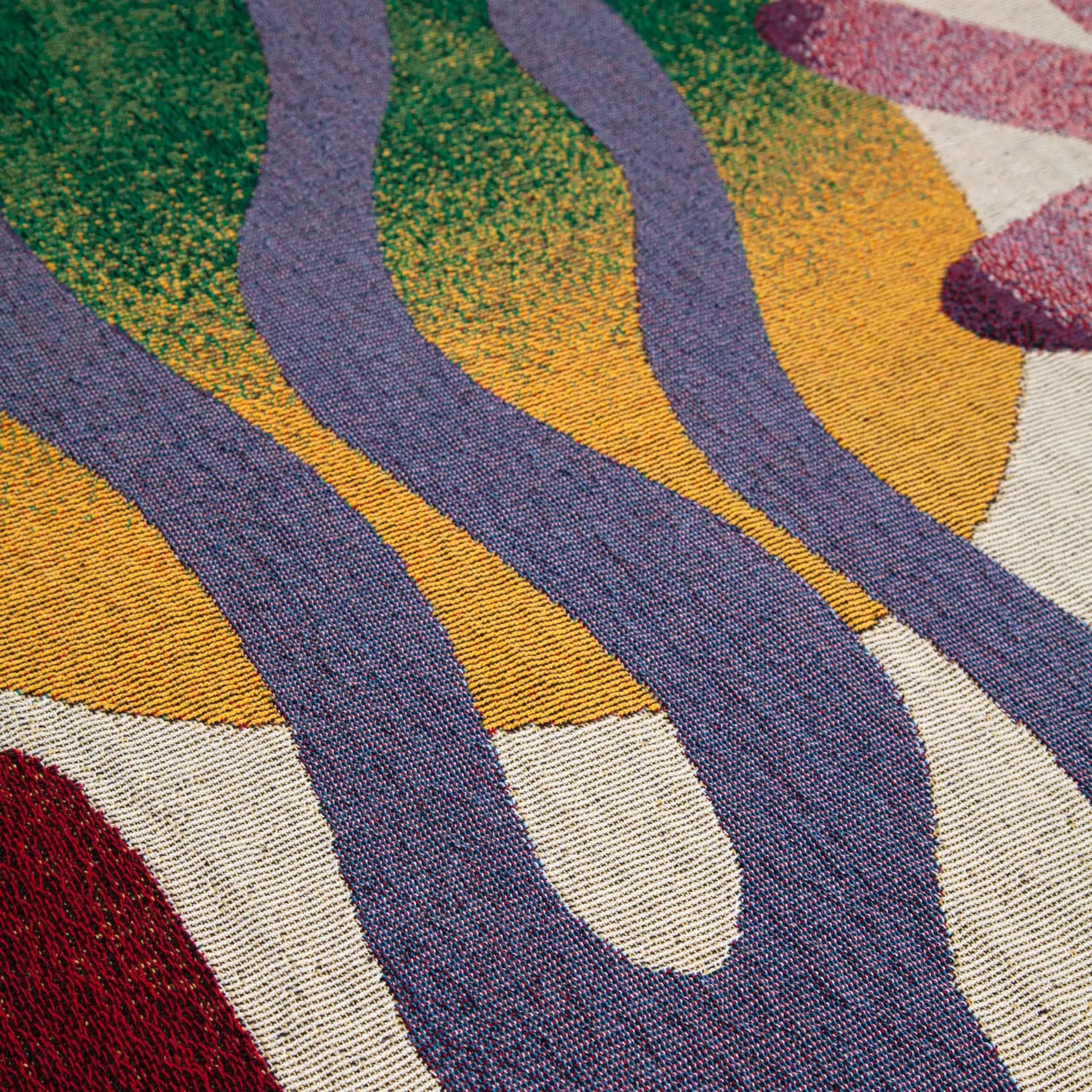 The Slowdown Studio Dumont Throw by Slowdown Studio features abstract textile art with curving purple lines, a yellow oval, and green and red textured areas on beige, crafted from recycled cotton in bold, organic patterns.