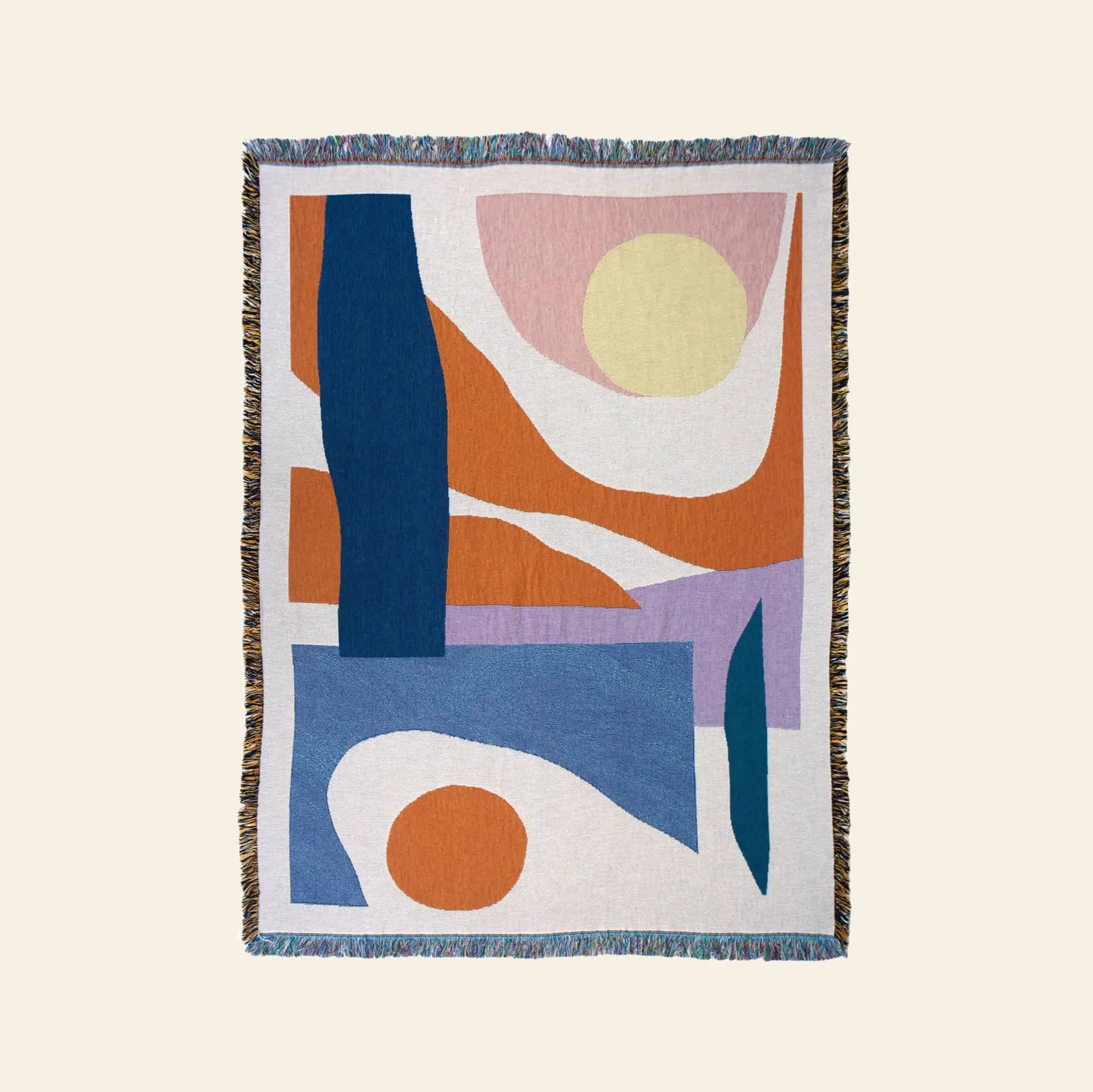 The Slowdown Studio Essien Throw is a woven blanket crafted from recycled cotton, featuring abstract shapes in blue, orange, yellow, lavender, and white with colorful fringed edges for a modern artistic accent.
