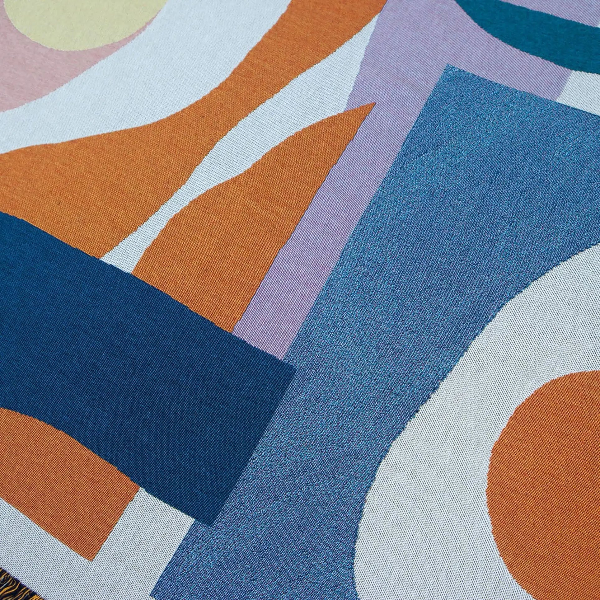 The Slowdown Studio Essien Throw features an abstract design of overlapping geometric shapes in blue, orange, white, lavender, and pale yellow on recycled cotton for a modern look.