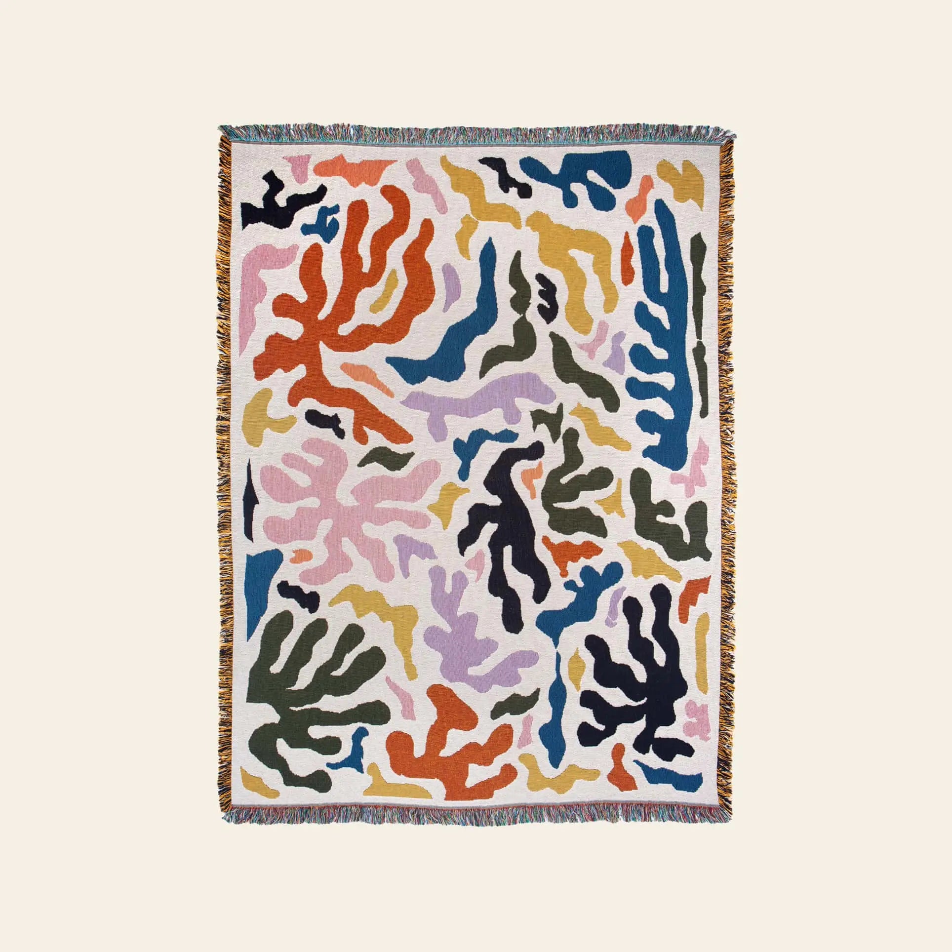 The Slowdown Studio Mercer Throw is a recycled cotton woven blanket with an abstract pattern in vibrant colors, finished with multicolored fringe edges.