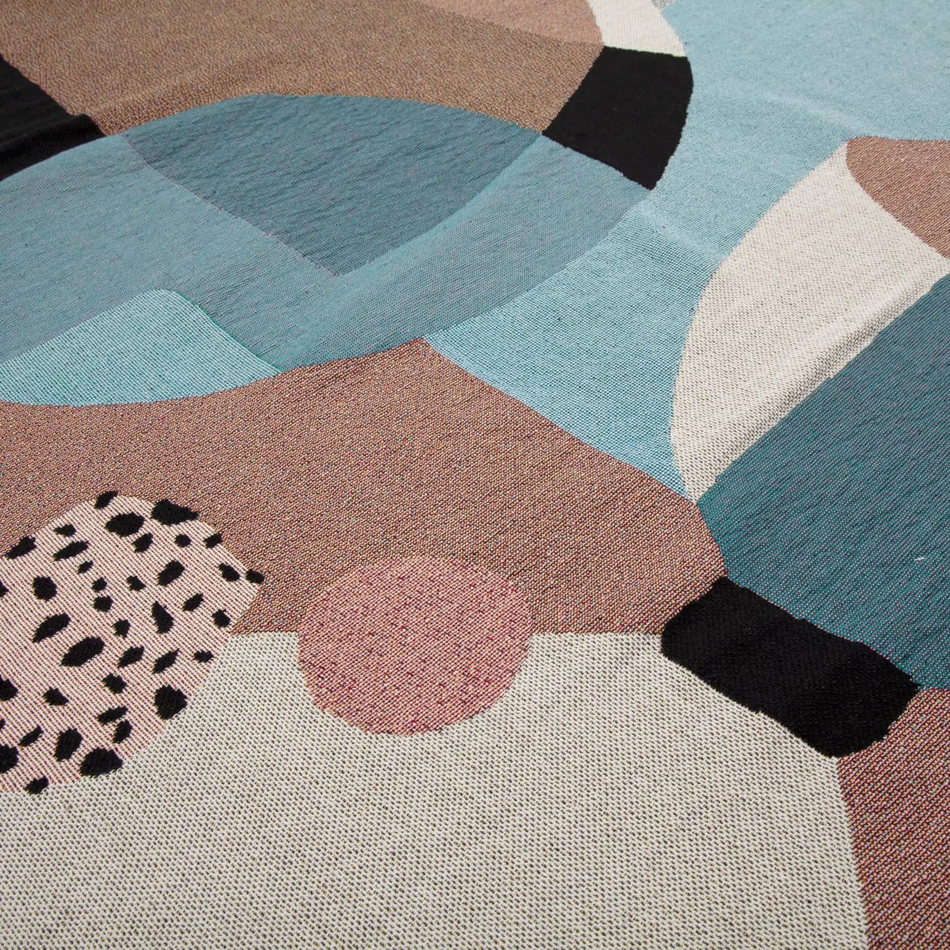 Close-up of the Slowdown Studio Pollard Throw, featuring abstract overlapping shapes in blue, beige, pink, black, and white. Crafted from recycled cotton with varied textures and patterns, this eco-friendly throw combines style and sustainability.