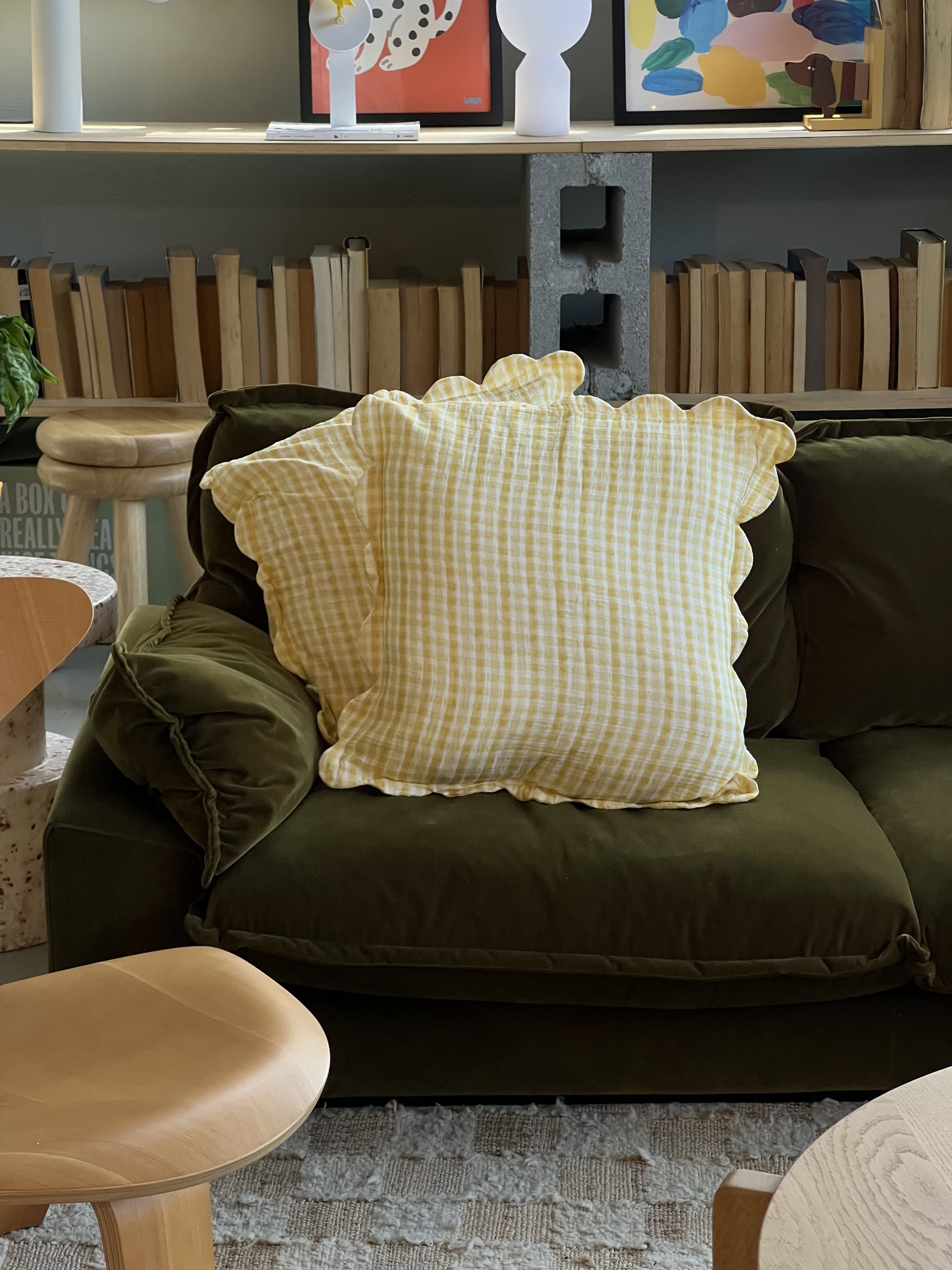 The Soft Spot Soft Petal Cushion Covers, Set of 2, from Soft Spot—one in yellow gingham and the other in colorful florals—decorate a beige couch, with neutral curtains in the background.
