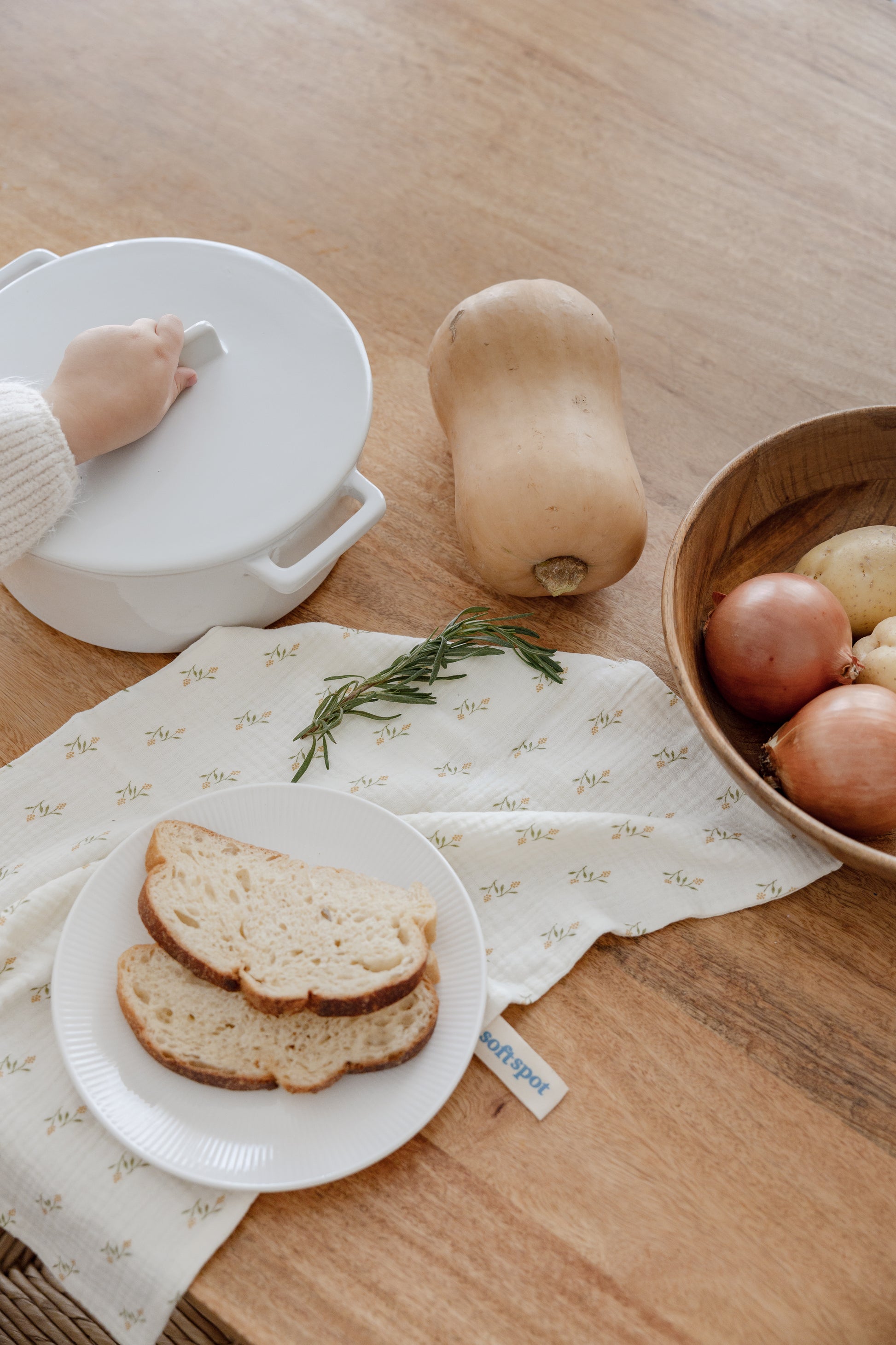 The Soft Spot Soft Tea Towels (Set of 3) by Soft Spot features yellow, cream, and rust towels, neatly folded and tied with a white ribbon on a plain light background—ideal for use as tea or hand towels.