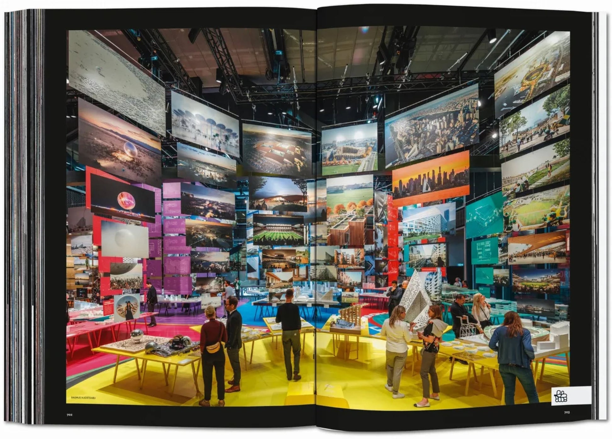 Visitors view TASCHEN BIG. Formgiving. An Architectural Future History by TASCHEN, with vibrant architectural images on display around yellow tables atop a lively, multicolored floor.