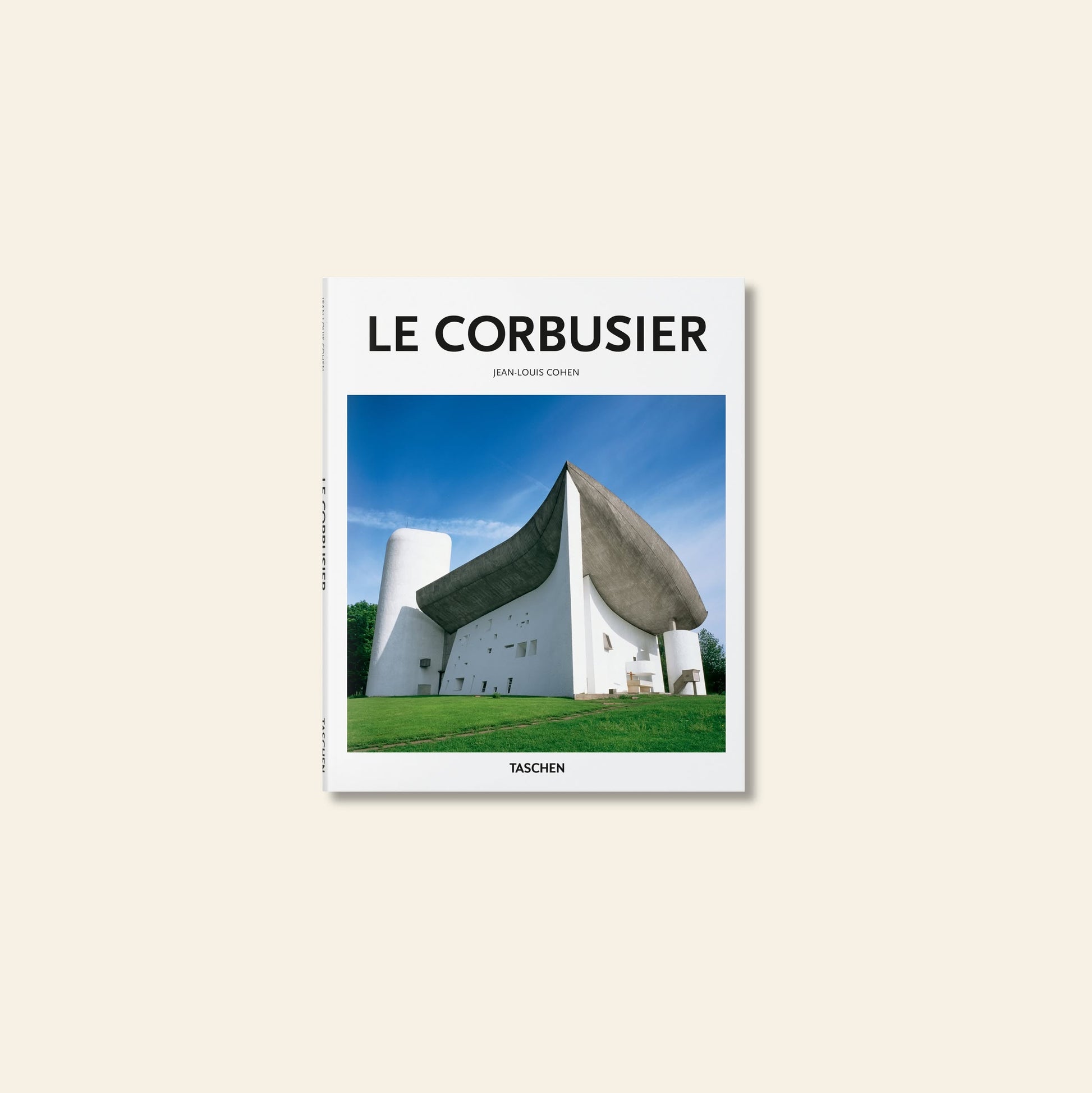 Book cover of TASCHEN Le Corbusier features a striking photograph of the sculptural Notre-Dame du Haut chapel with its curved concrete roof against a blue sky, highlighting an iconic moment in modern architecture. Brand: TASCHEN.