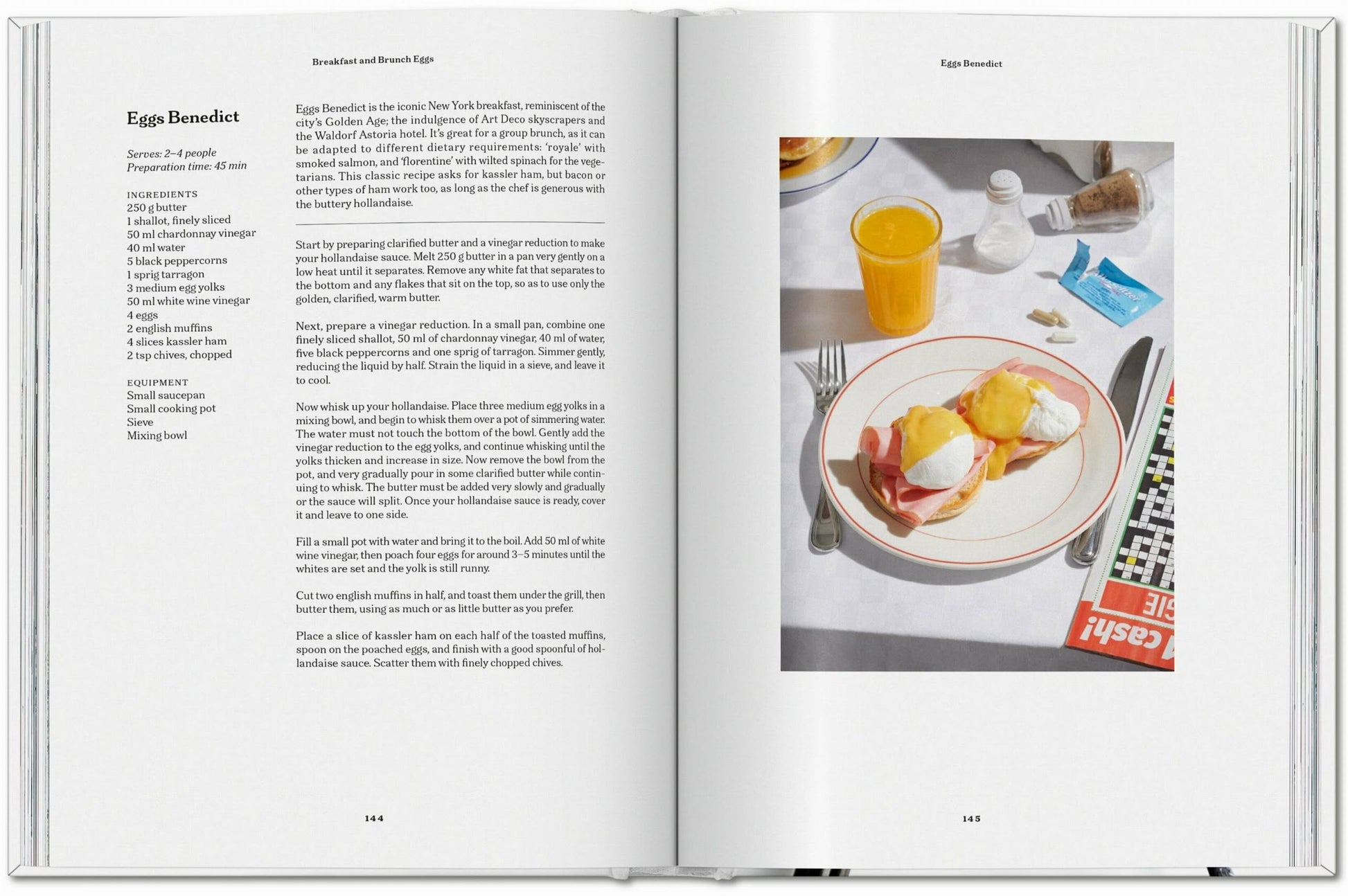 The TASCHEN The Gourmandʼs Egg: A Collection of Stories and Recipes by TASCHEN is open, showing a unique Eggs Benedict recipe alongside a photo of two eggs Benedict, orange juice, utensils, a napkin, and a crossword puzzle.