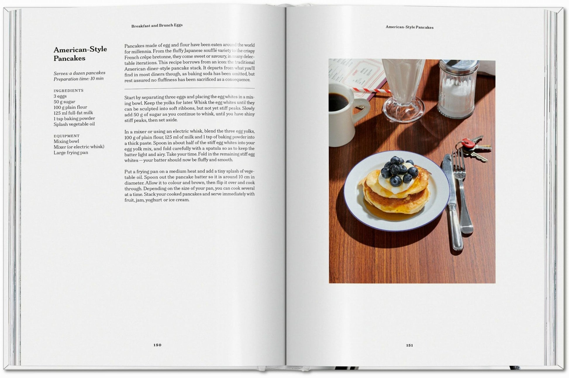 The TASCHEN The Gourmand’s Egg cookbook lies open on a rustic wooden table, with an egg pancake recipe and a vibrant photo of pancakes topped with blueberries, syrup, and coffee—blending food artistry from TASCHEN.
