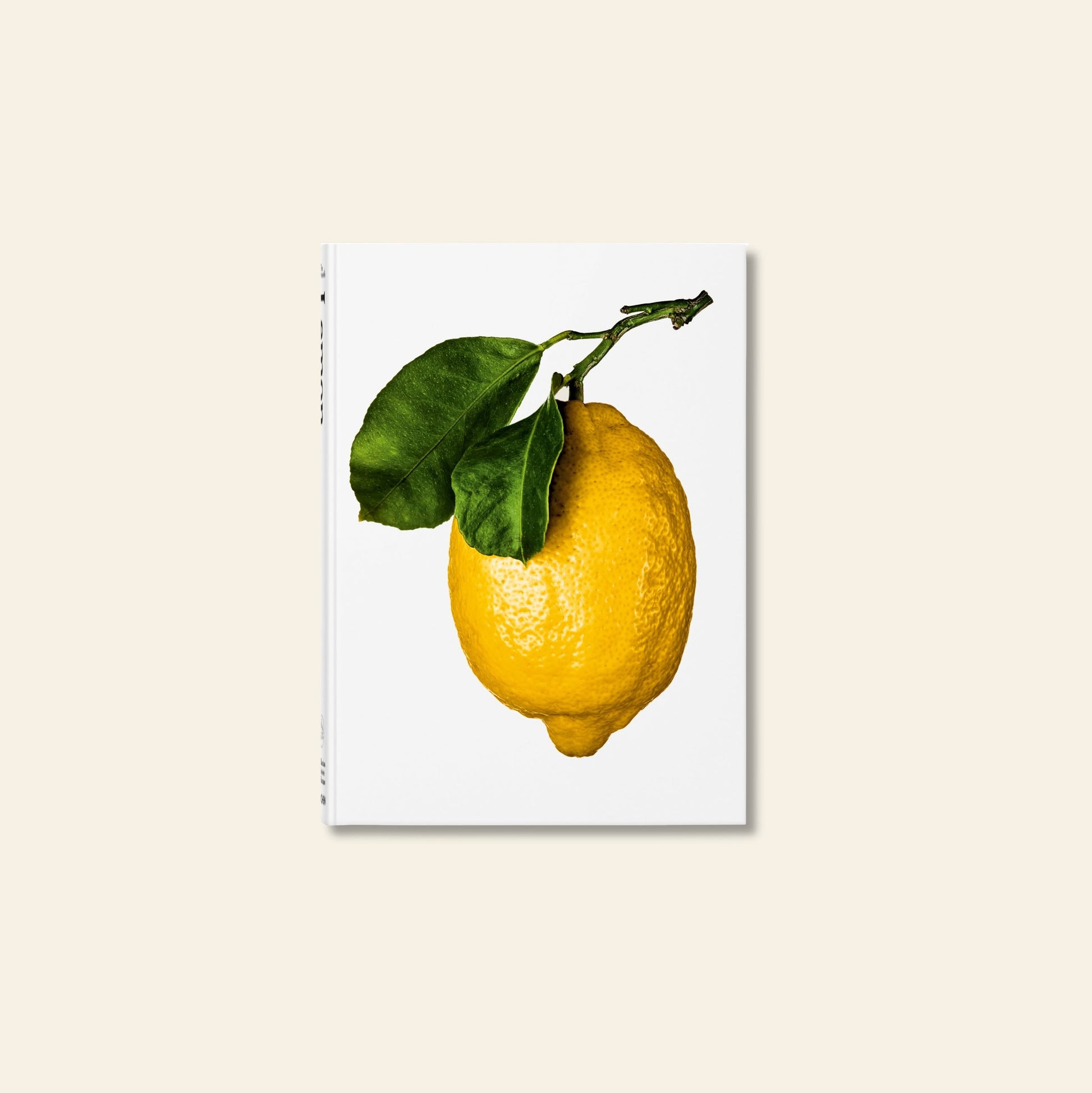 TASCHEN The Gourmands Lemon: A Collection of Stories and Recipes features a striking yellow lemon with green leaves on a white cover, ideal for lemon lovers and food enthusiasts. Book by TASCHEN, centered on a light beige surface.