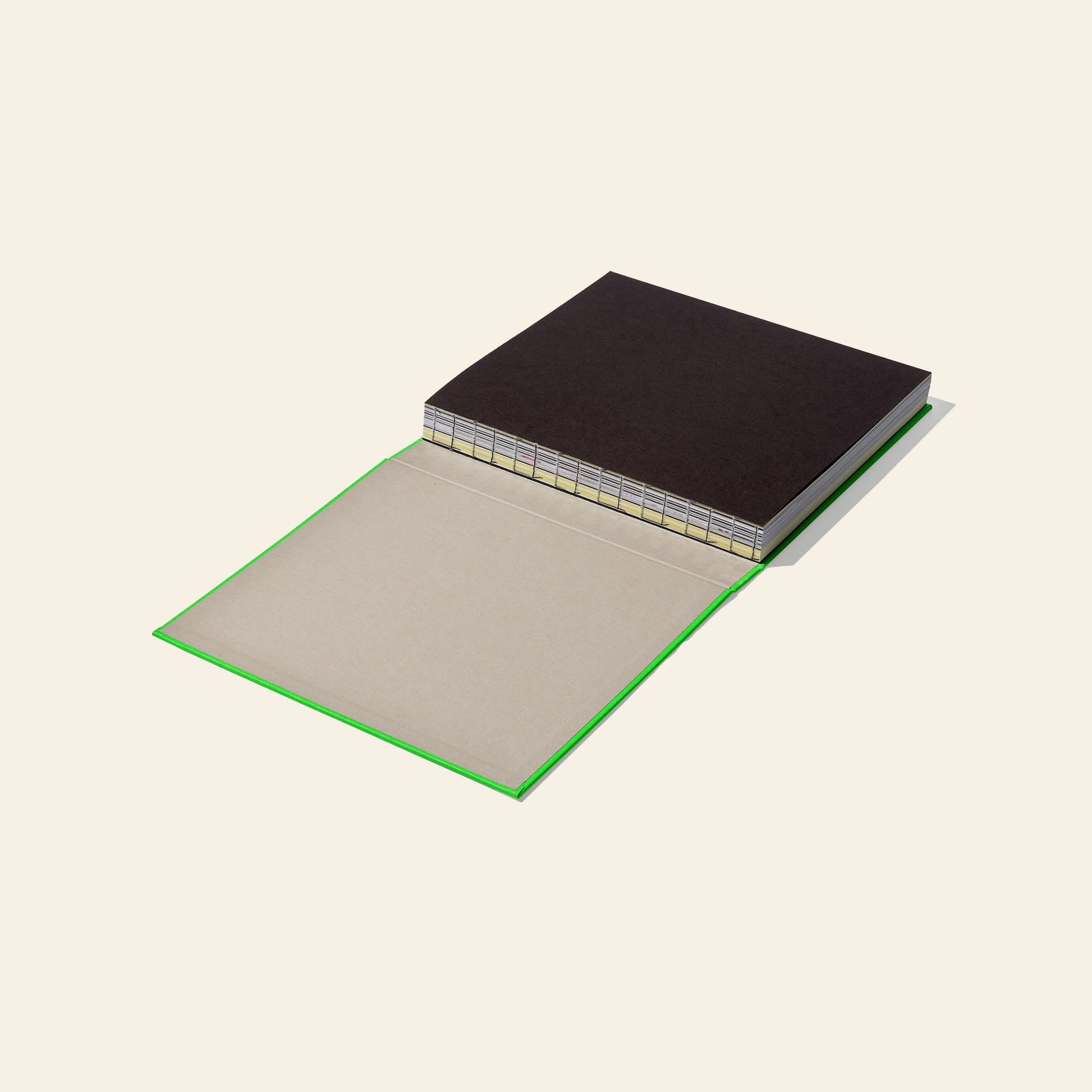 The TASCHEN Virgil Abloh. Nike: ICONS notebook, with a black cover, green edges, and exposed spine binding inspired by The Ten, is displayed on a light beige background showing its blank pages.