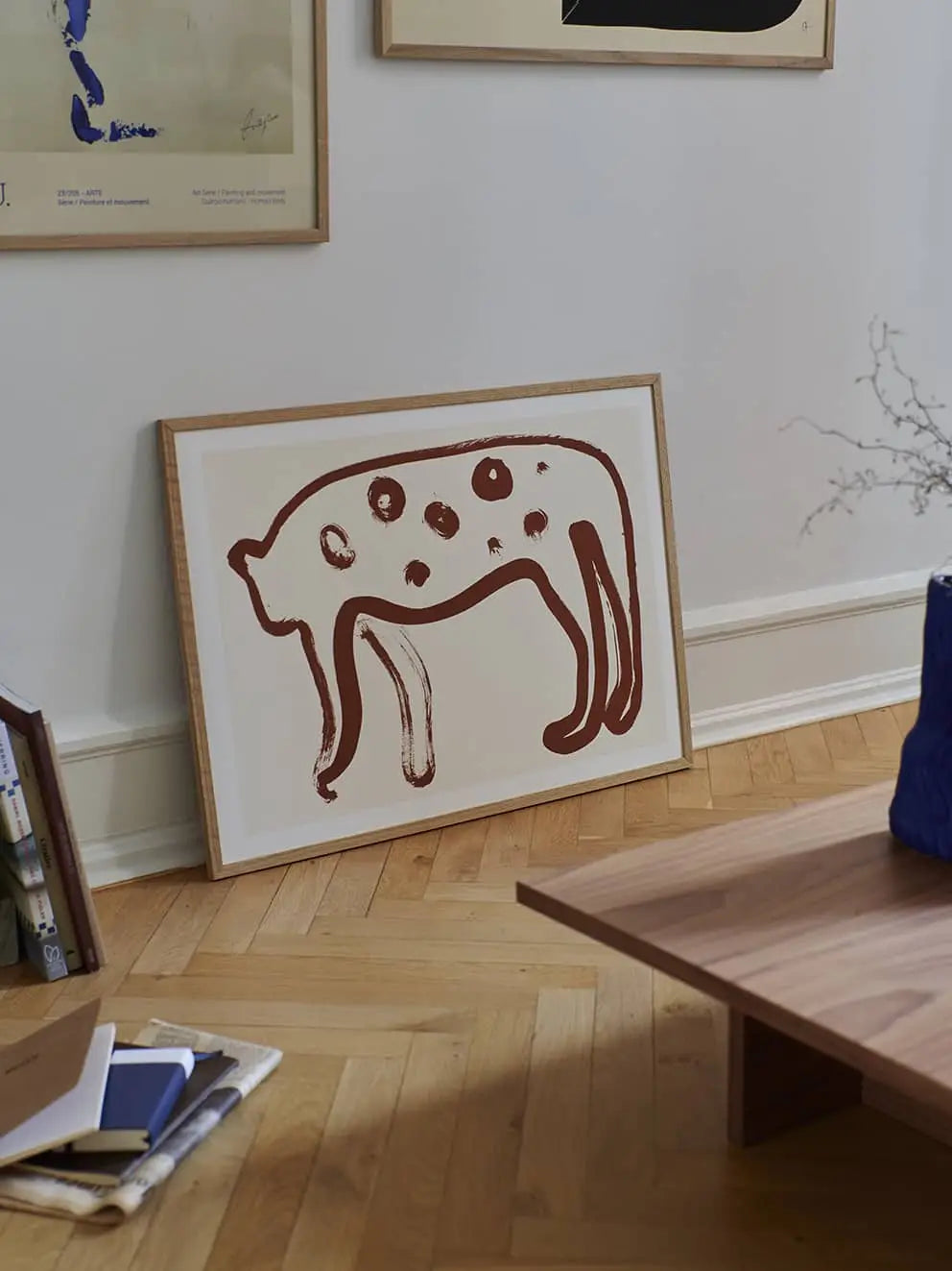 A framed Jaguar 01 abstract art print by Anastasia Krasilnikova from The Poster Club (50x70 cm) leans against a white wall in a modern room with wooden flooring and minimal decor.
