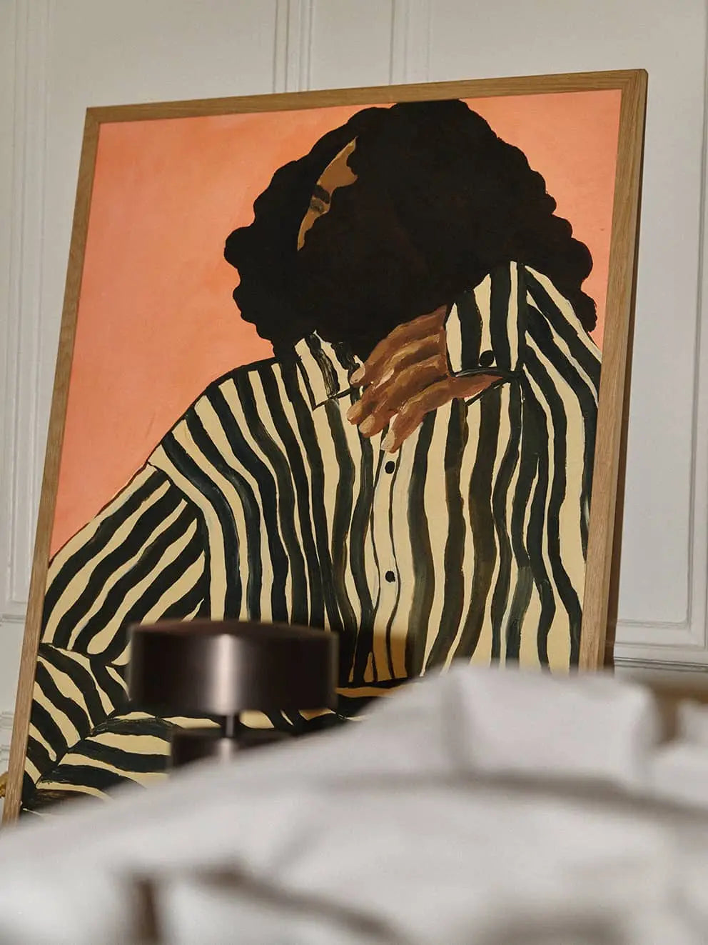 The Poster Club Anna Johansson - Monday (30x40) Art print shows a person with curly hair in a black and white striped shirt against a peach background, leaning on the wall. Find it at The Poster Club.