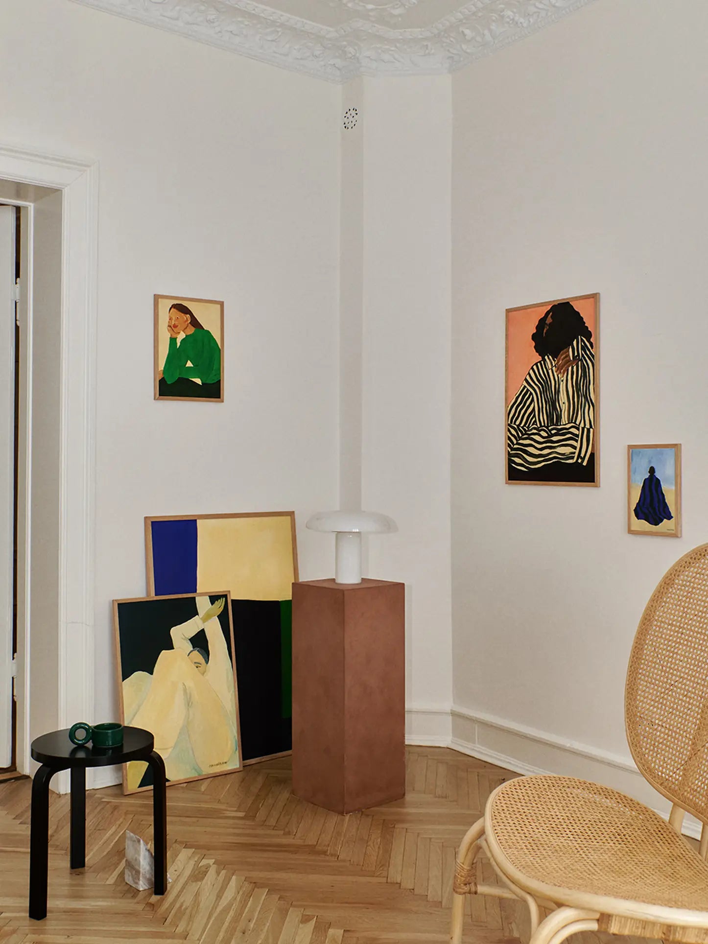 A stylish room with light walls and wooden floors features The Poster Club’s Hanna Peterson - The Book (50x70) print, bringing elegant portrait art and abstract figures inspired by chic interiors from leading design magazines.