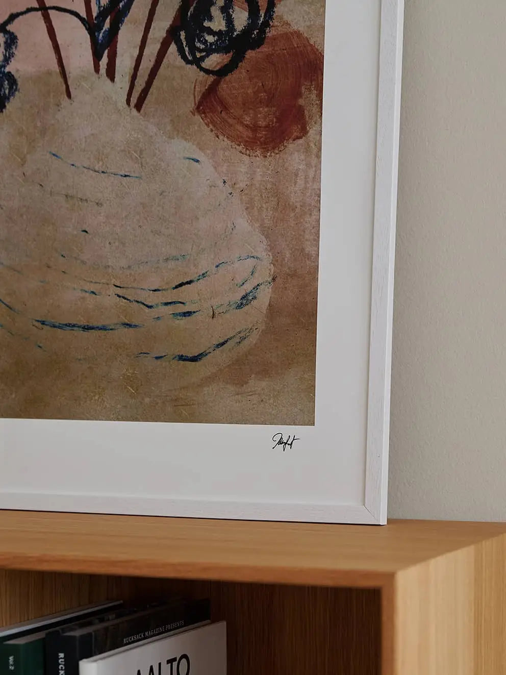 A corner of The Poster Club Madelen Möllard - Flowers in Blue Vase (50x70) art print is visible above a light wooden shelf lined with books, showcasing its earthy tones and dark lines.