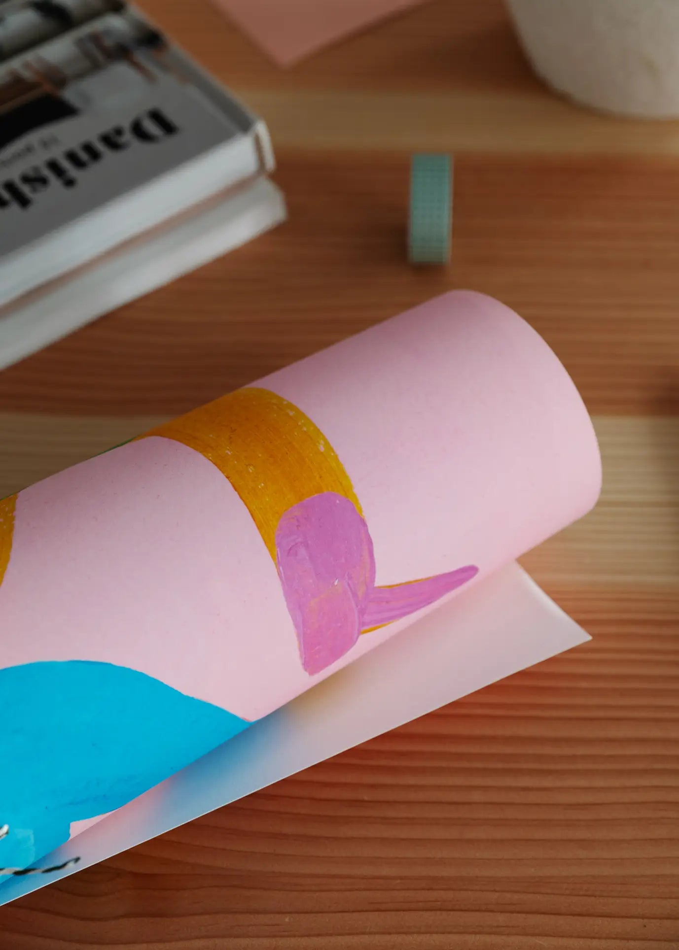 A close-up of Walk The Walk (50x70) by Lise Uhrskov for The Poster Club, featuring rolled pink paper with blue, orange, and purple paint on wood—ideal as a unique fine art print.