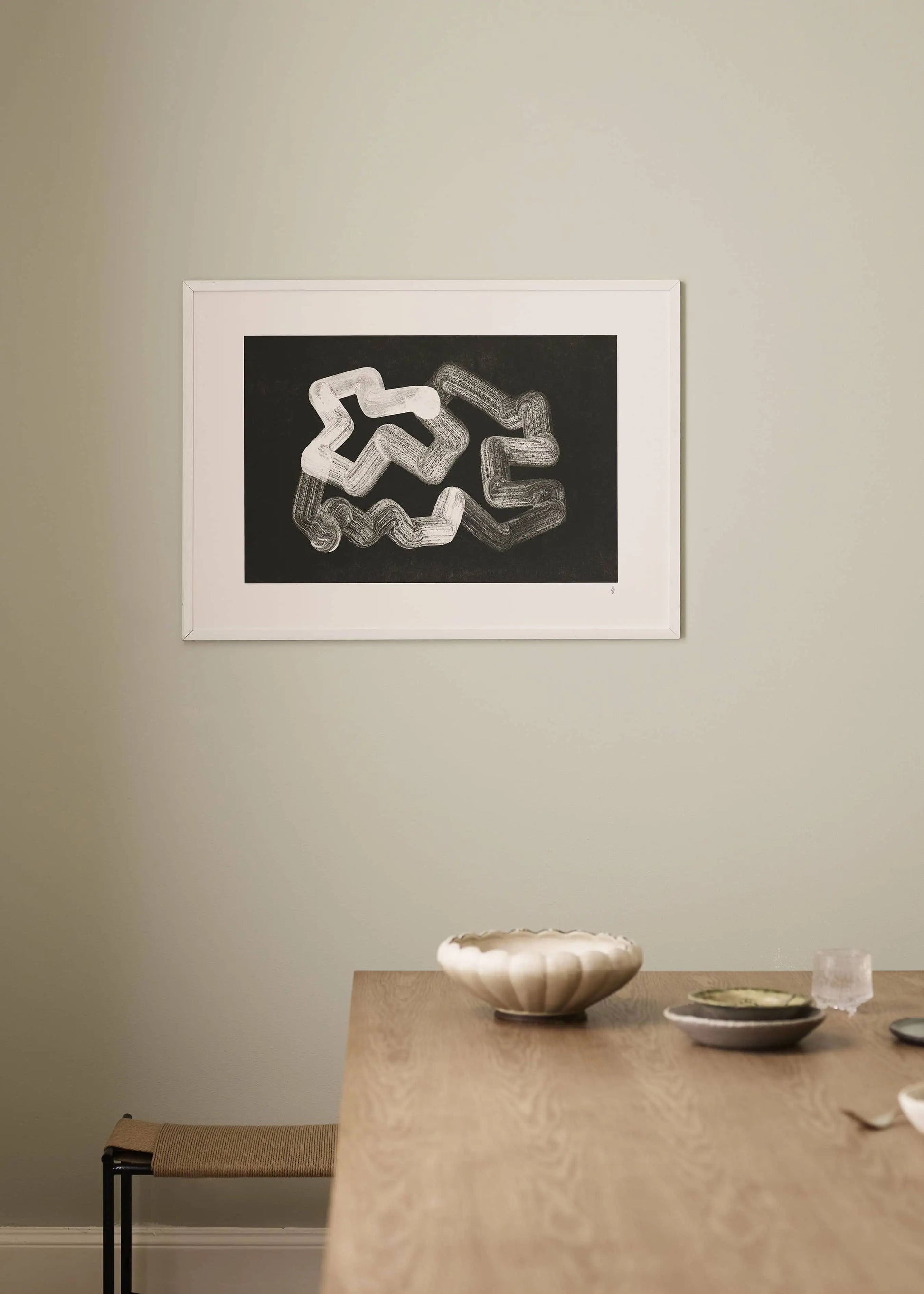 A minimalist room with a light wall features The Poster Club Anastasia Krasilnikova - Jaguar 01 (50x70) art print. Below, a wooden table holds a ribbed ceramic bowl, small dish, and glass for a simple modern feel.