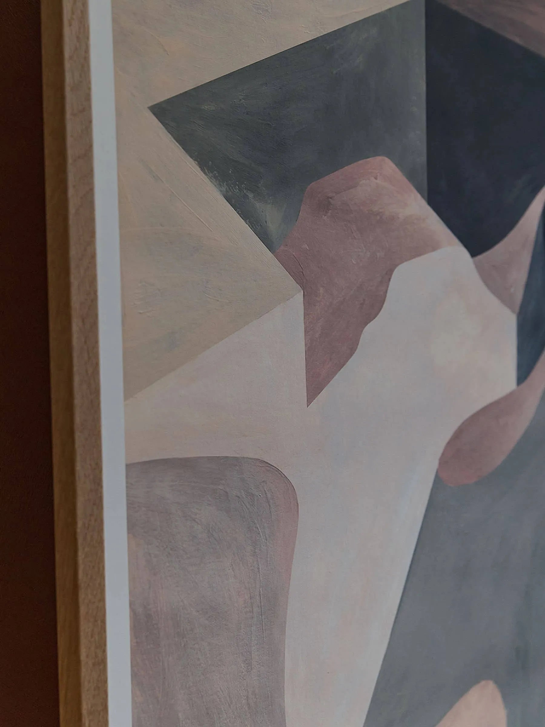 Close-up of the edge of The Poster Club’s The Lipko Project - Empty Skatepark 02 (30x40): an abstract giclée print with soft geometric shapes in beige, pink, gray, and black, framed by a light wooden border.