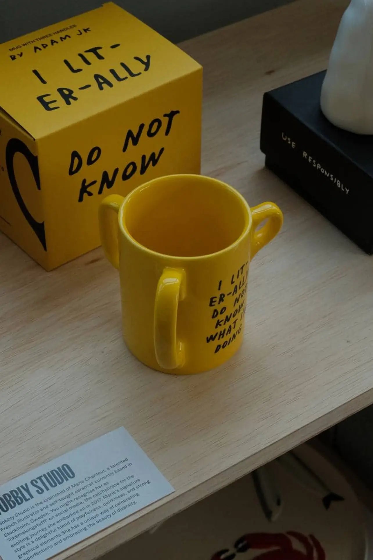 A yellow Third Drawer Down Adam JK - I Literally Do Not Know Mug with three handles sits on wood, featuring a playful handwritten quote in bold black, with matching box.