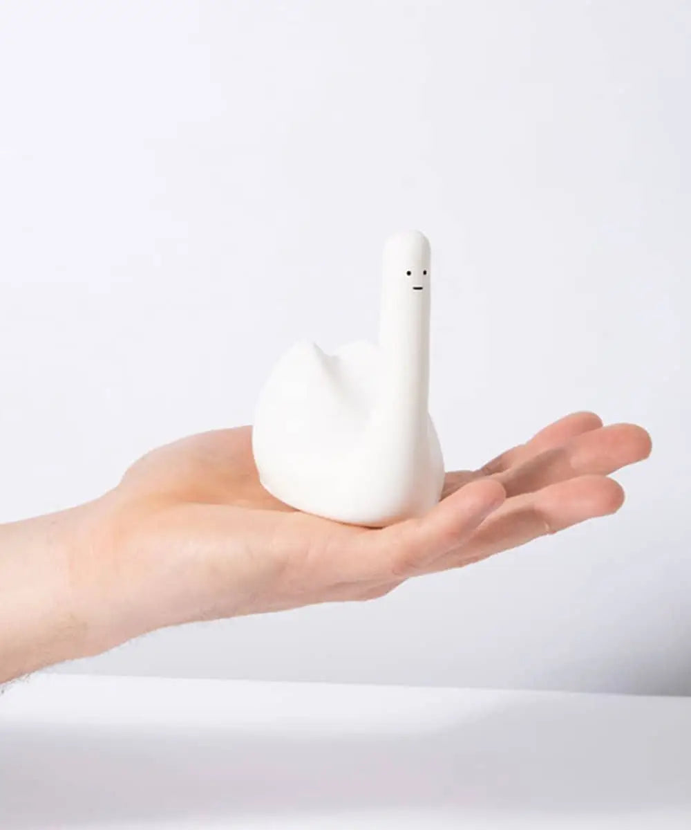 A person holds the Third Drawer Down David Shrigley - Ridiculous Stress Swan-Thing, a whimsical white stress toy with a simple face on its neck—an amusing, quirky gift by Third Drawer Down for any occasion, shown against a plain white background.