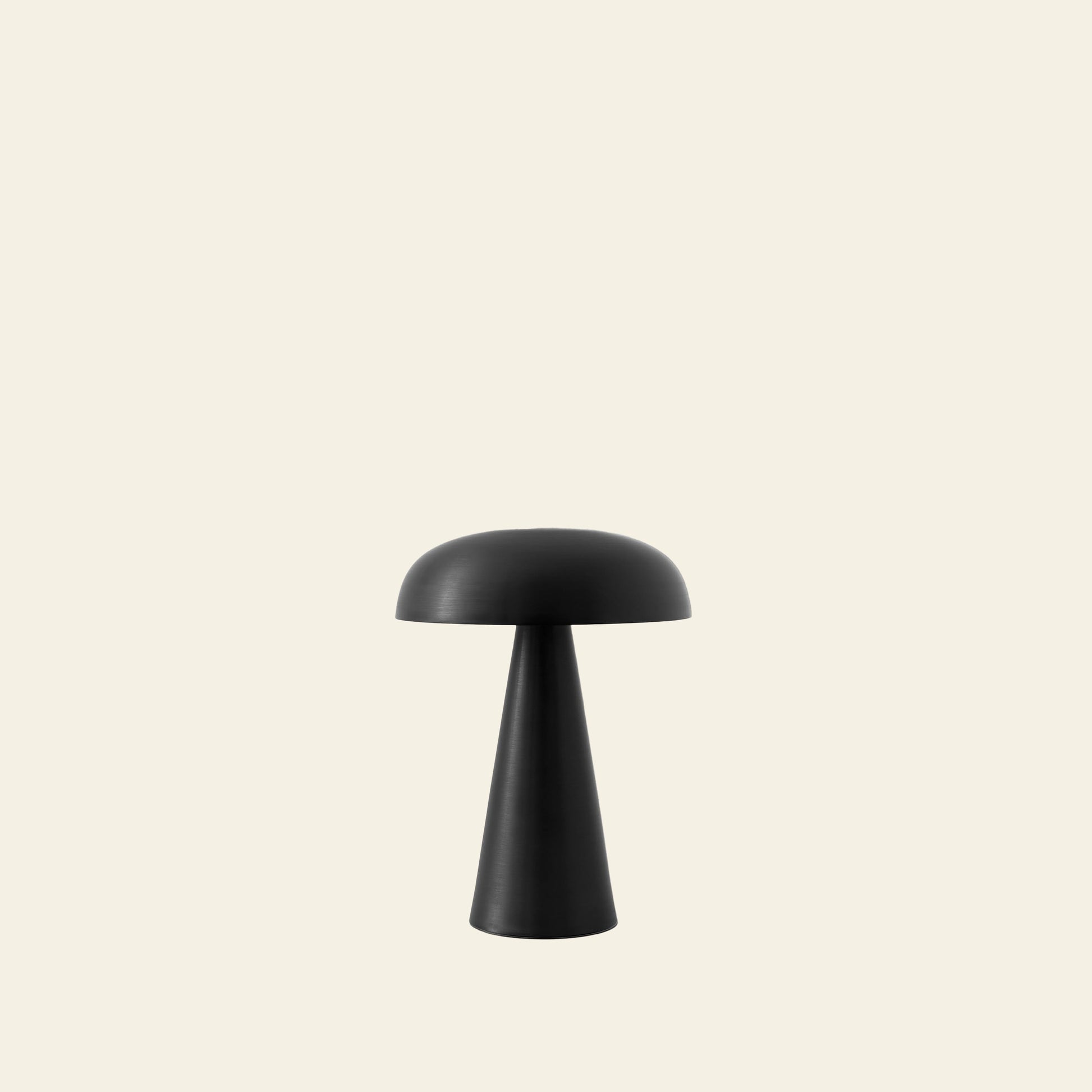 The &Tradition Como SC53 Portable Table Lamp by &Tradition features a minimalist black dome shade and conical base, set against a light beige background. It offers rechargeable convenience and adjustable lighting for versatile use.