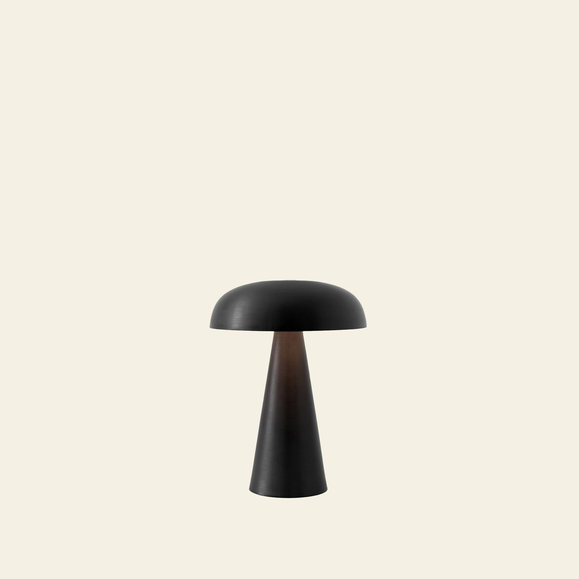 The &Tradition Como SC53 Portable Table Lamp, by &Tradition, features a modern black finish with a dome shade and conical base. Centered on a light beige background, this rechargeable lamp offers adjustable lighting for versatile use.