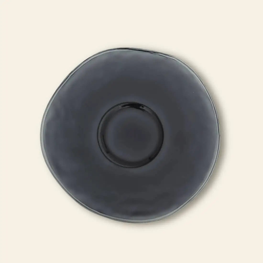 The Urban Nature Culture Dinner Plate Recycled Glass features an irregular shape and glossy dark gray finish, giving it a rustic feel against a plain light beige background.