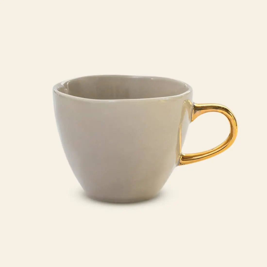 The Urban Nature Culture Good Morning Cup Mini is a plain beige ceramic mug with a shiny gold handle, shown against an off-white background.