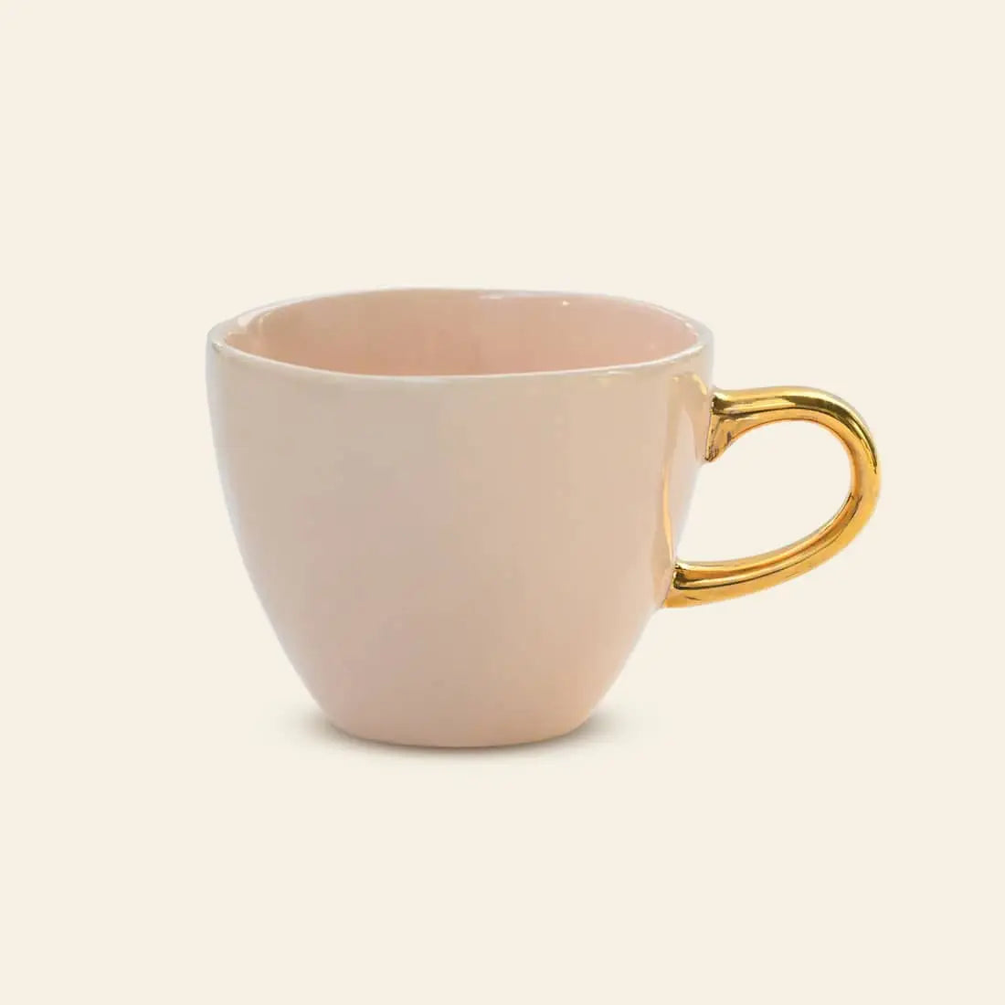 The Urban Nature Culture Good Morning Cup Mini by Urban Nature Culture is a light pink ceramic mug with a shiny gold handle, photographed against a plain light background.