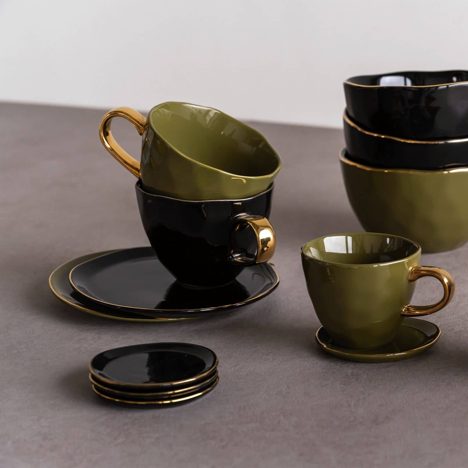 The Urban Nature Culture Good Morning Plate by Urban Nature Culture is elegantly designed in fir green and black with gold rims, paired with matching cups and saucers, all displayed neatly on a gray surface.