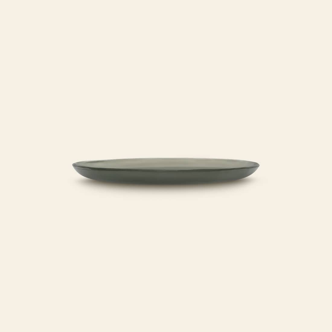 The Urban Nature Culture Plate Recycled Glass Frost is a simple, round recycled plate with a slightly raised rim in dark green, shown from the side against a light beige background.