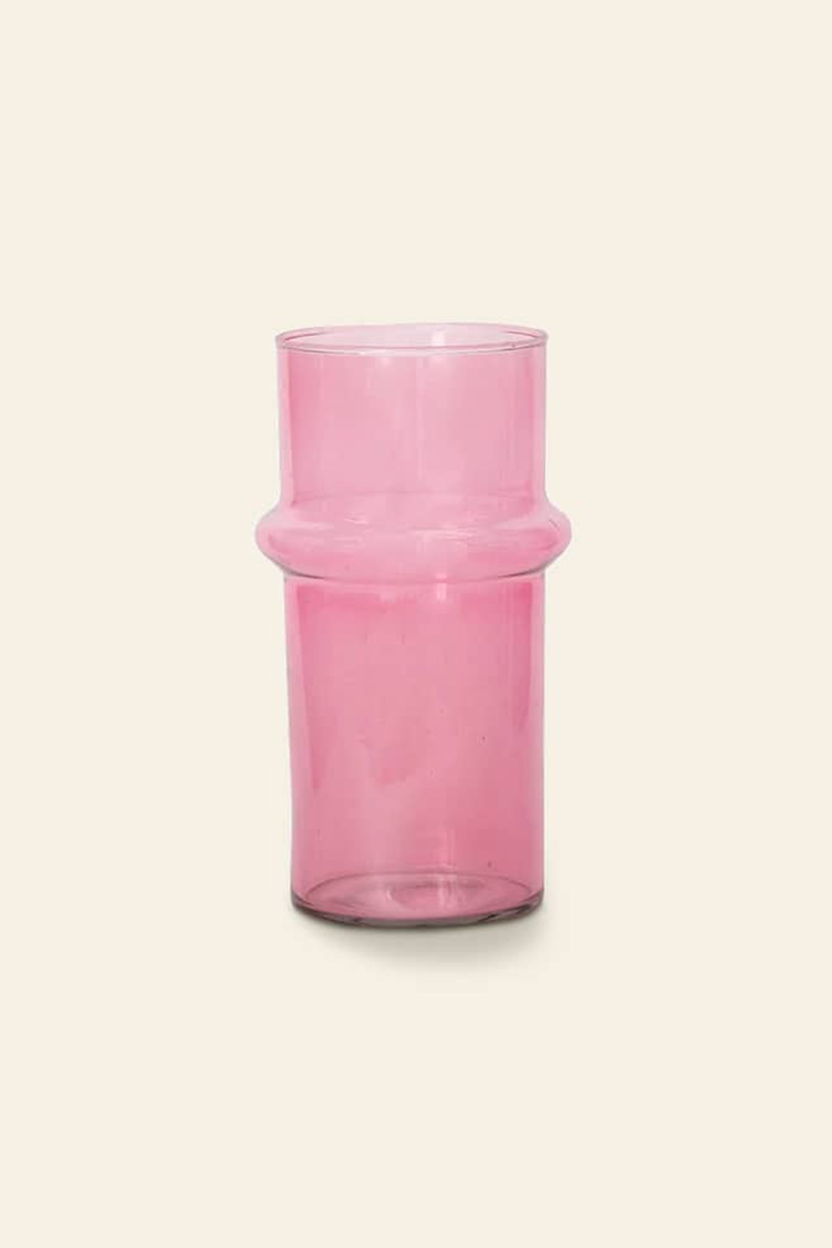 The Urban Nature Culture Vase Recycled Glass, Pink features a gently rounded ridge around the middle, bringing a charming touch to your decor when placed against a plain beige background.