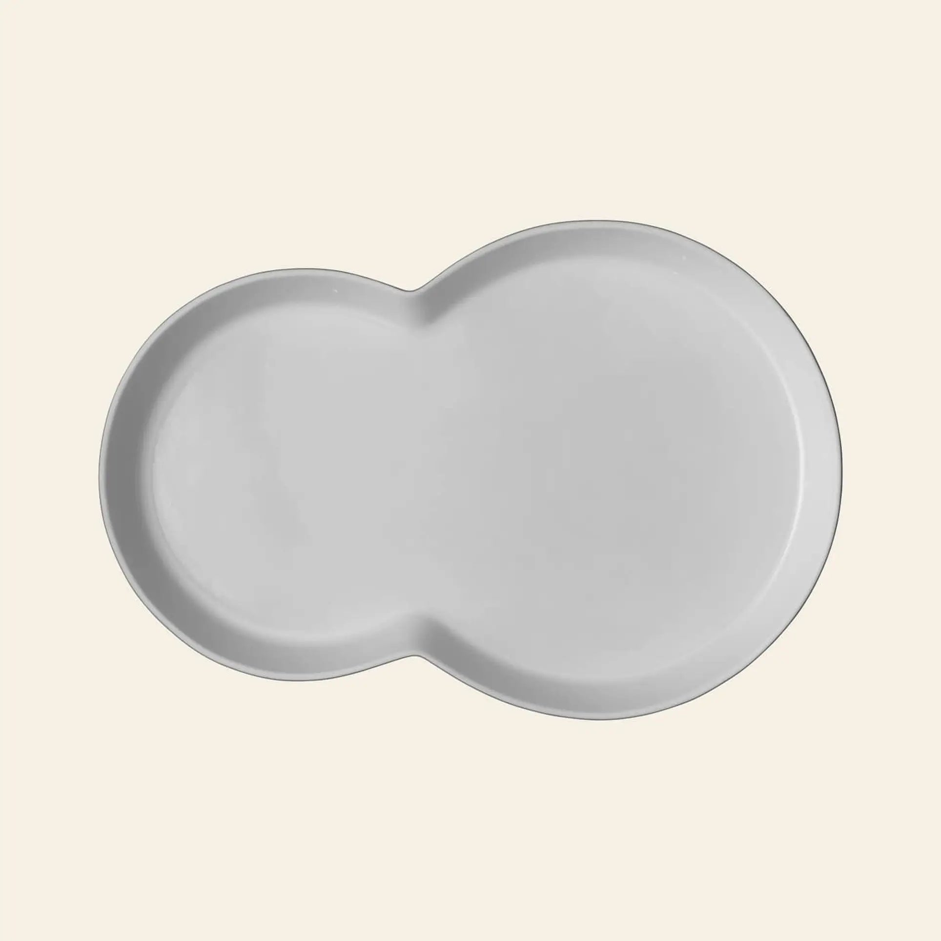 The Vipp Vipp214 Brunch Plates, Set of 2 by Vipp feature a white, kidney-shaped ceramic design with smooth edges—ideal as a modern centerpiece for stylish gatherings. Shown here against a plain light beige background.