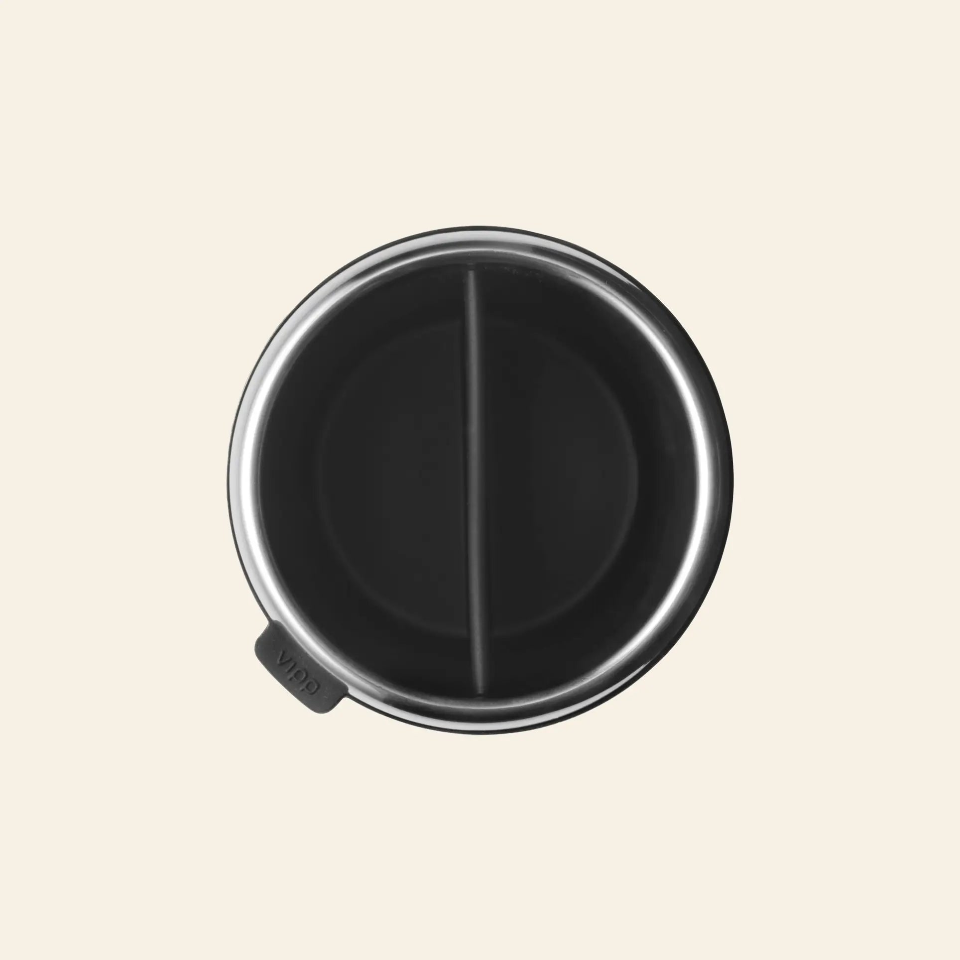 A top-down view of the Vipp Vipp7 Toothbrush Holder by Vipp shows its stainless steel exterior and black interior, divided into two sections by a central divider—ideal for use as a stylish bathroom essential. Features a silver body with a small black tab.