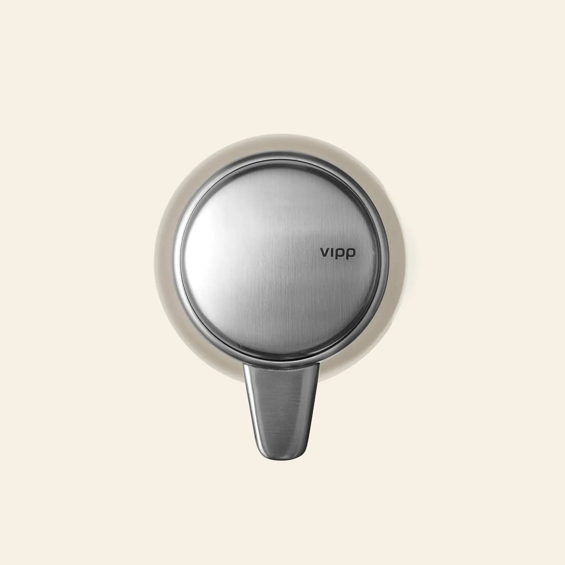The Vipp Vipp9 Dispenser, featuring a modern stainless steel design and the Vipp logo on the front, is shown mounted on a plain beige background—an elegant and practical kitchen accessory.